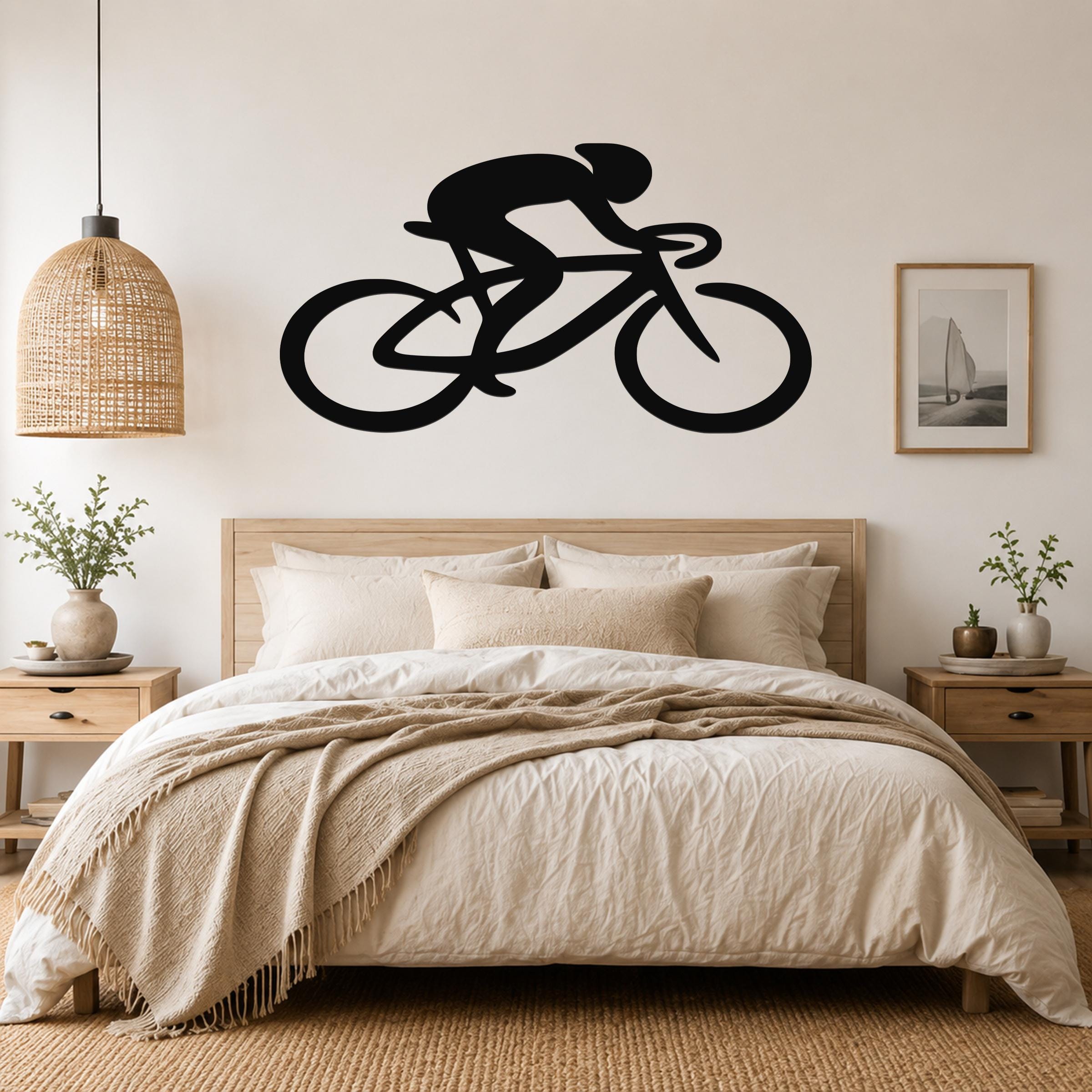 Black metal wall art featuring a cyclist silhouette in motion, mounted above a bed in a neutral bedroom.