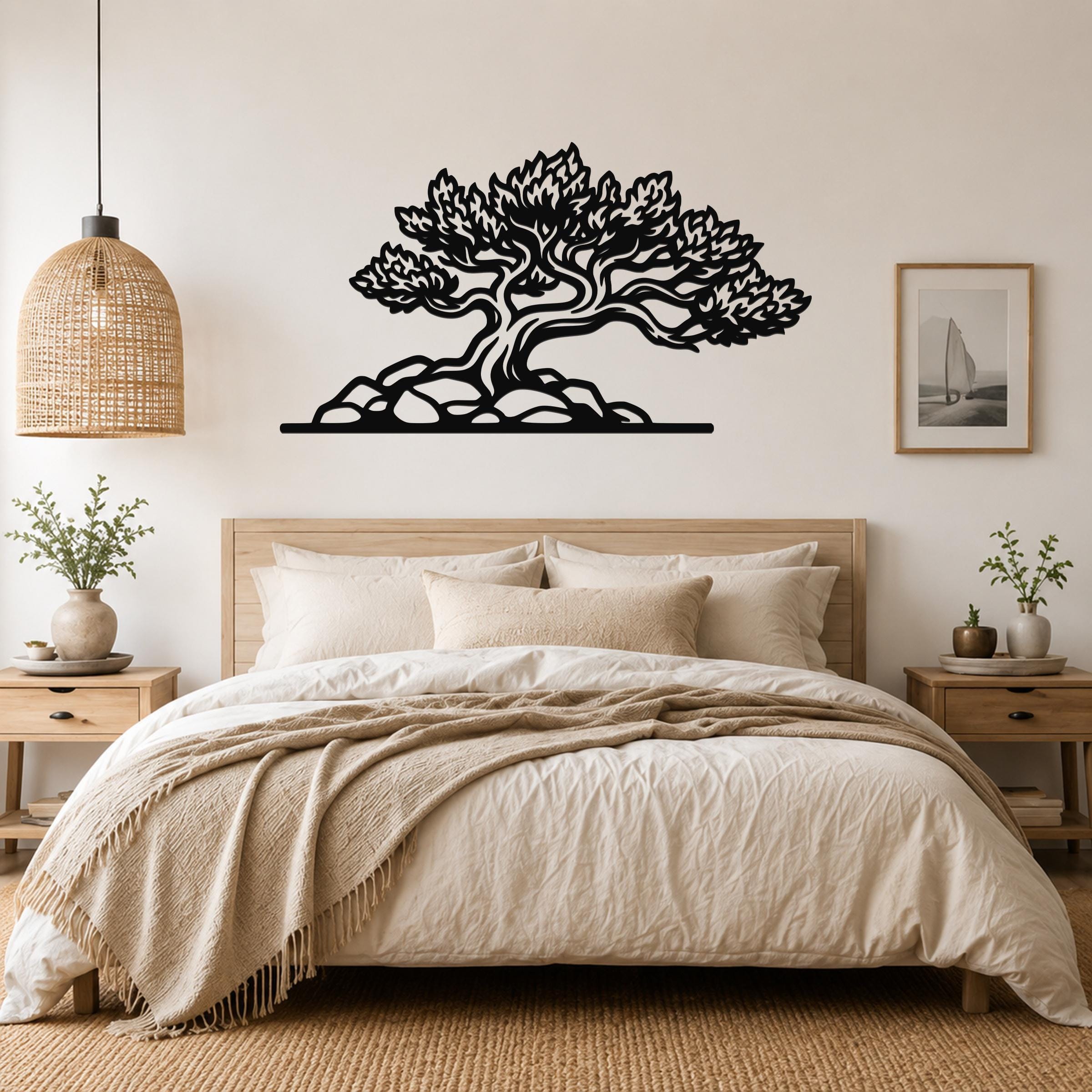 Black metal wall art of a juniper tree with intricate branch and leaf cutouts, mounted above a bed in a neutral bedroom.