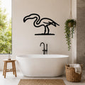 Black metal flamingo wall art silhouette mounted on a bathroom wall above a freestanding tub, with a hanging plant and woven basket nearby.