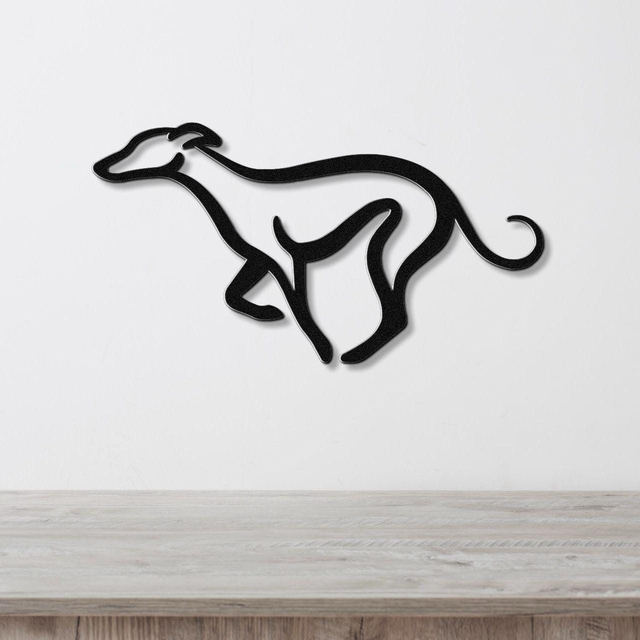 Black metal greyhound wall art with a minimalist silhouette design, mounted on a white wall above a light wood surface.