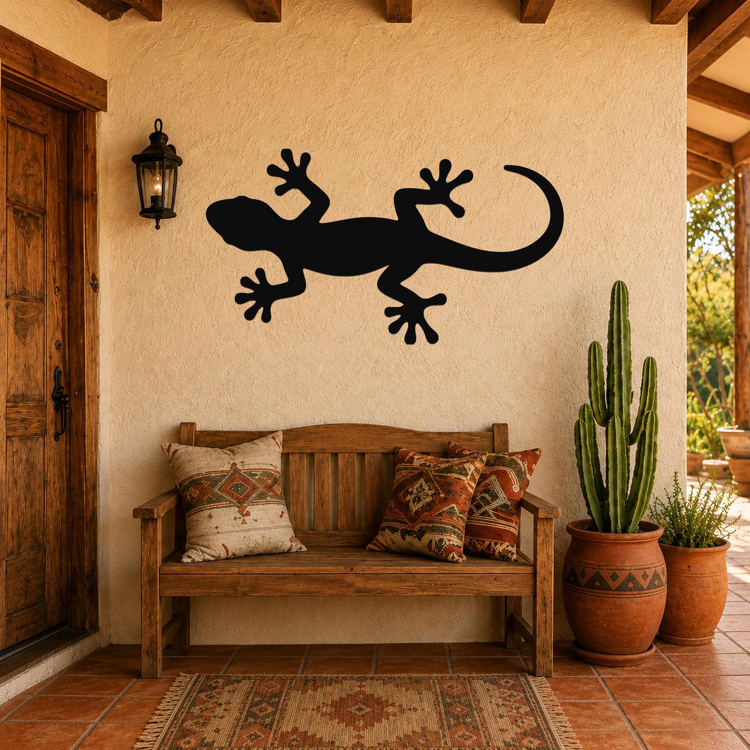 Black metal lizard wall art silhouette mounted on a stucco wall above a wooden bench in a rustic patio entryway.