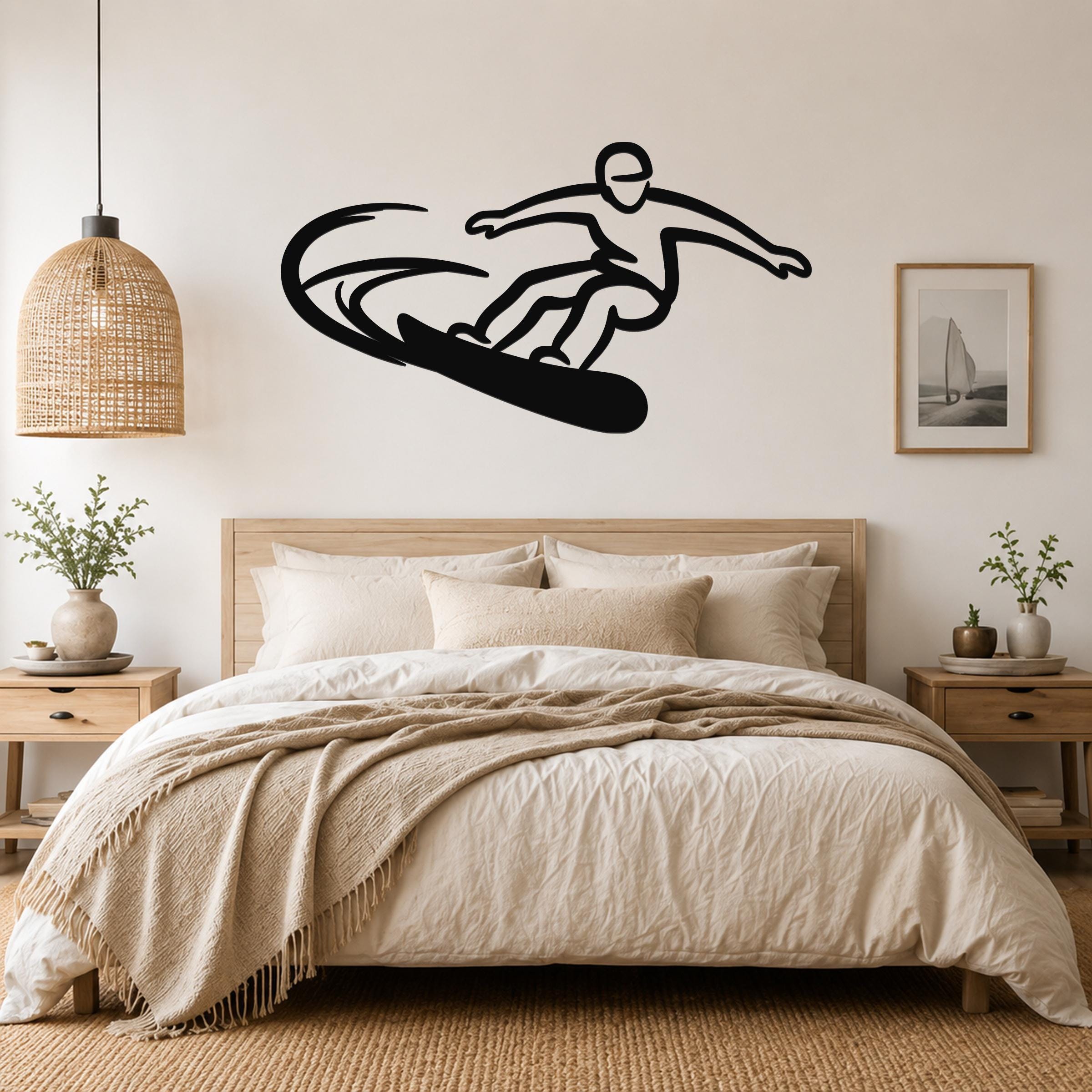 Black metal wall art silhouette of a snowboarder in motion, mounted above a bed in a neutral bedroom.