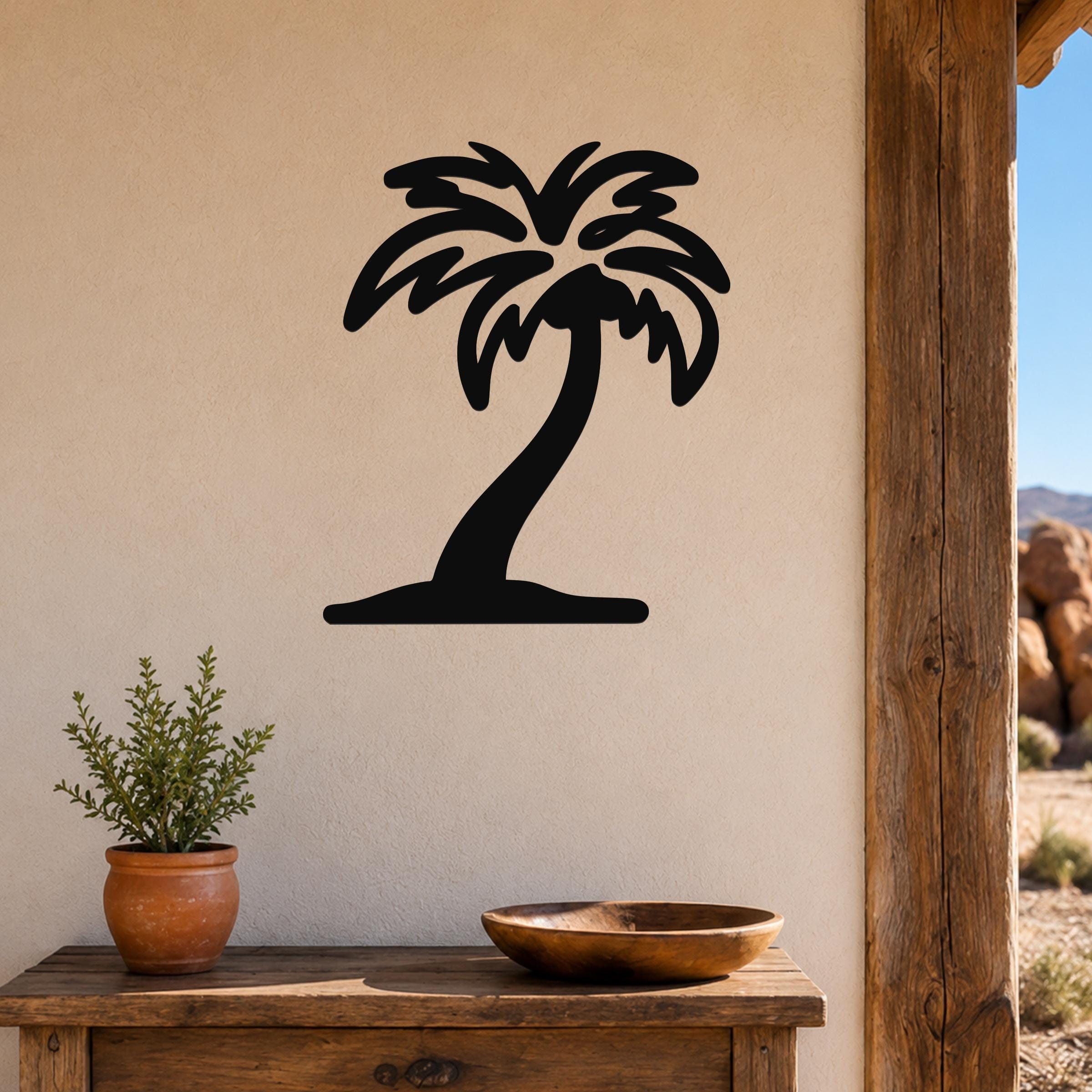 Black metal palm tree wall art with a silhouette design, mounted on a beige wall above a wooden table in a patio setting.