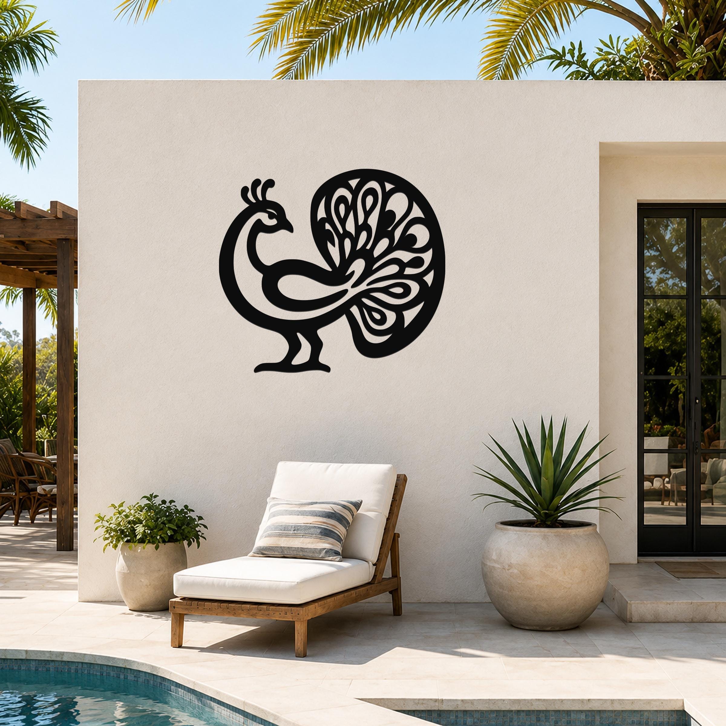 Black metal peacock wall art with intricate feather cutouts, mounted on a white outdoor wall beside a pool and lounge chair.