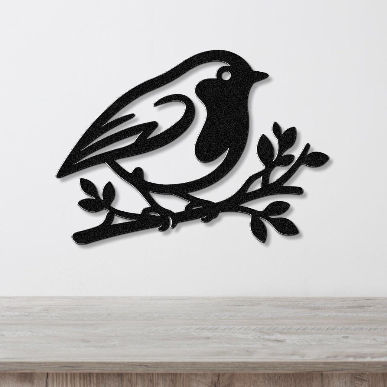 Black metal wall art featuring a robin silhouette perched on a branch, mounted on a white wall above a light wood surface.