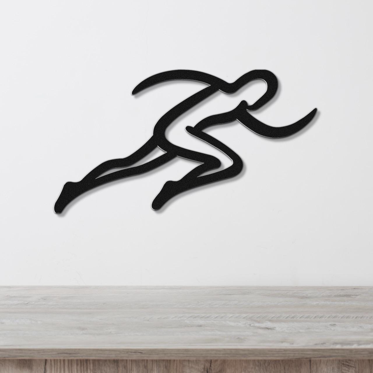 Black metal runner wall art with motion-line cutouts, mounted on a white wall above a light wood counter.