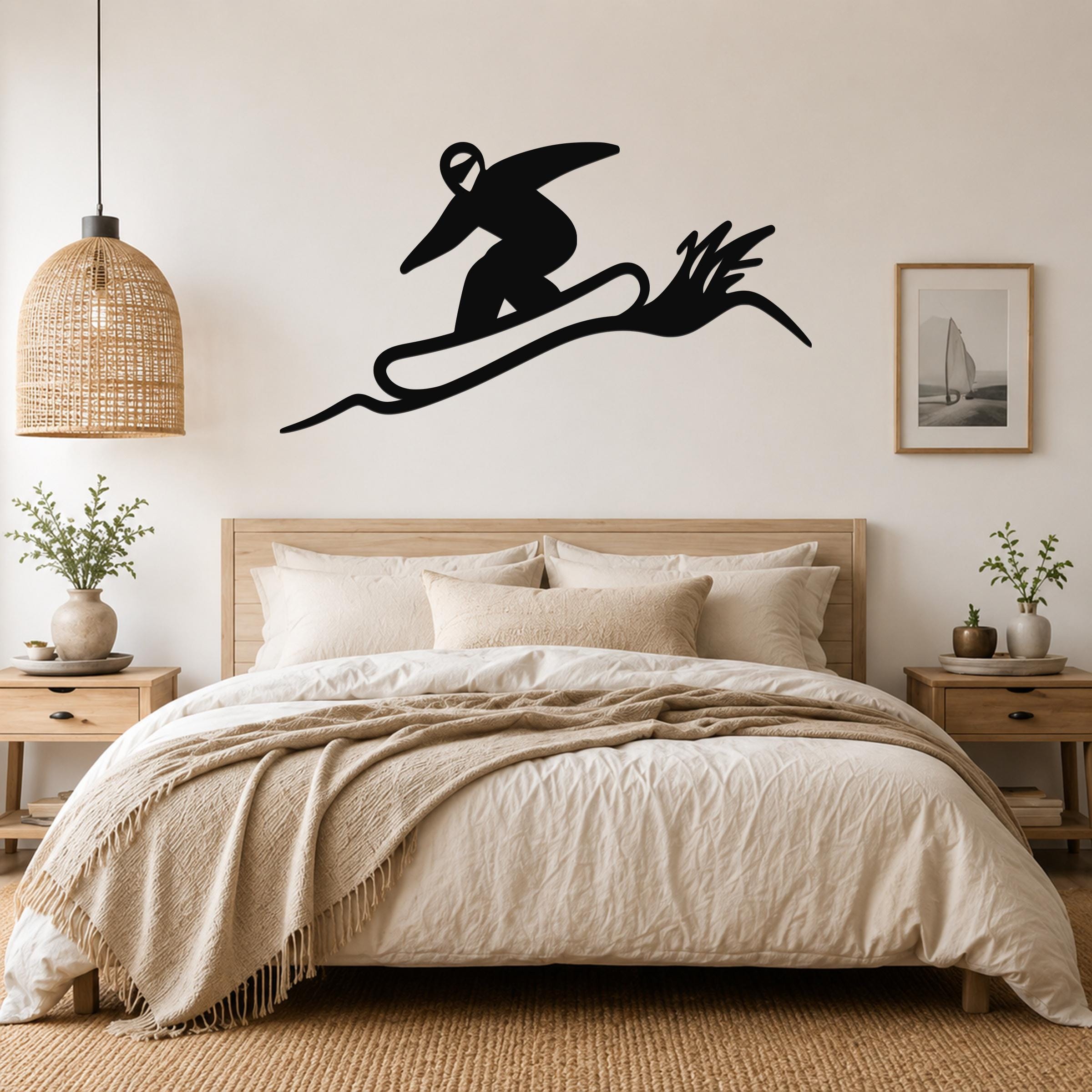 Black metal wall sculpture of a snowboarder in motion, mounted above a bed in a bedroom.