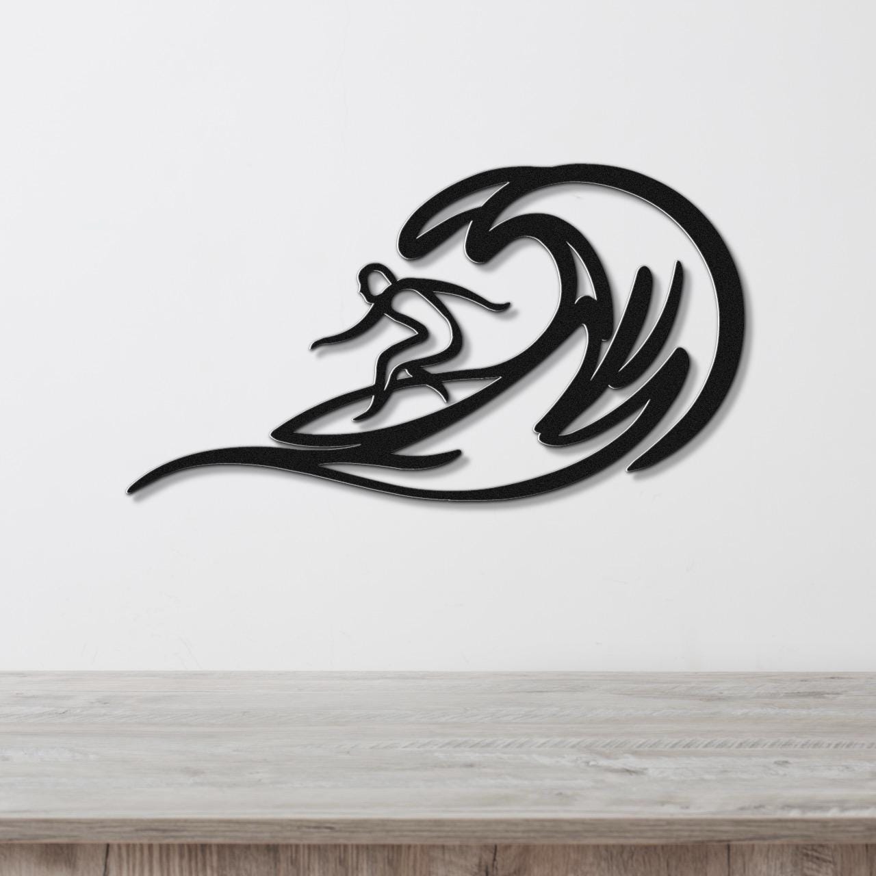 Black metal surfer wall art with wave cutouts, mounted on a white wall above a wooden counter.