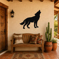 Black metal coyote wall art in a howling silhouette, mounted on a stucco wall above a wooden bench in a southwestern-style entryway.