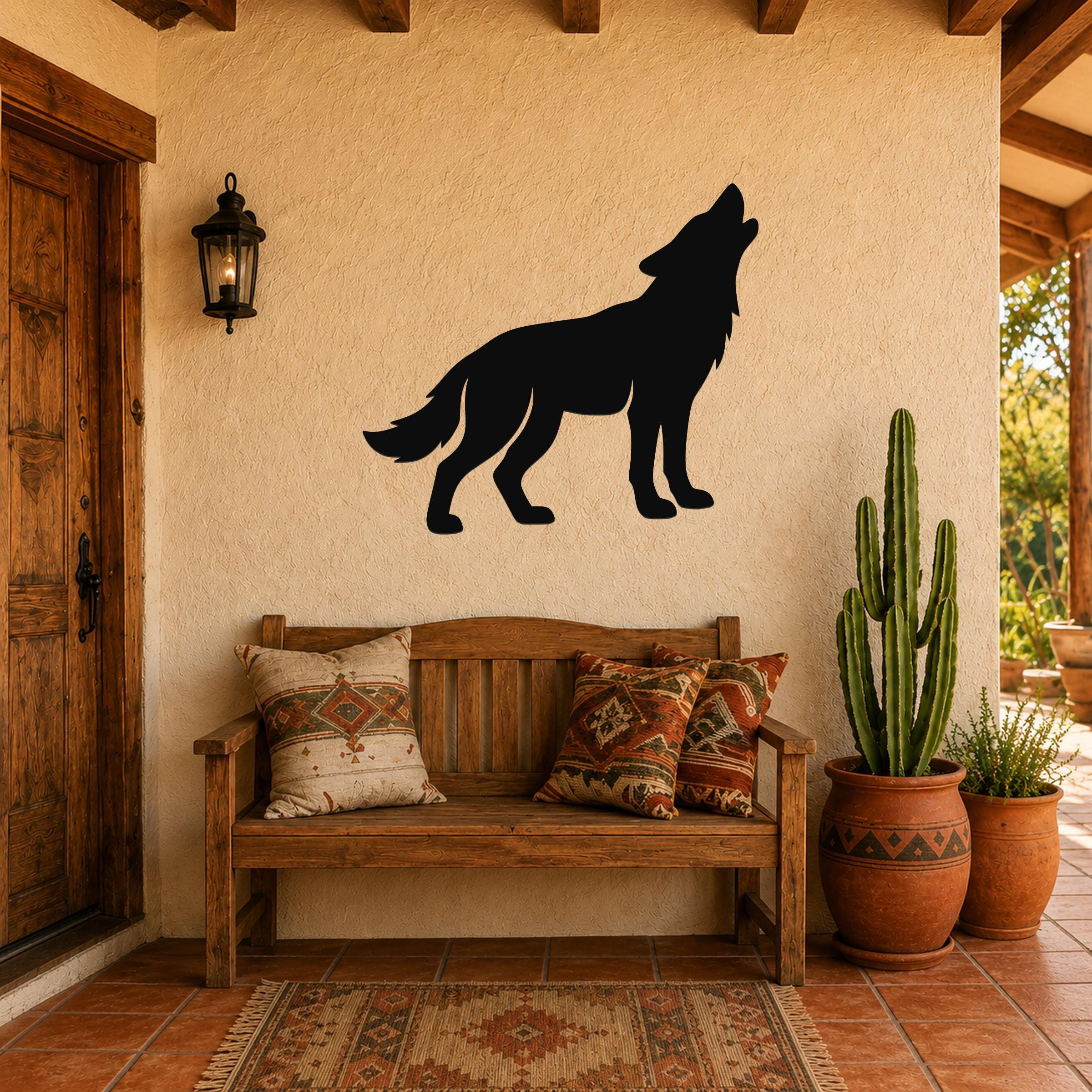 Black metal coyote wall art in a howling silhouette, mounted on a stucco wall above a wooden bench in a southwestern-style entryway.