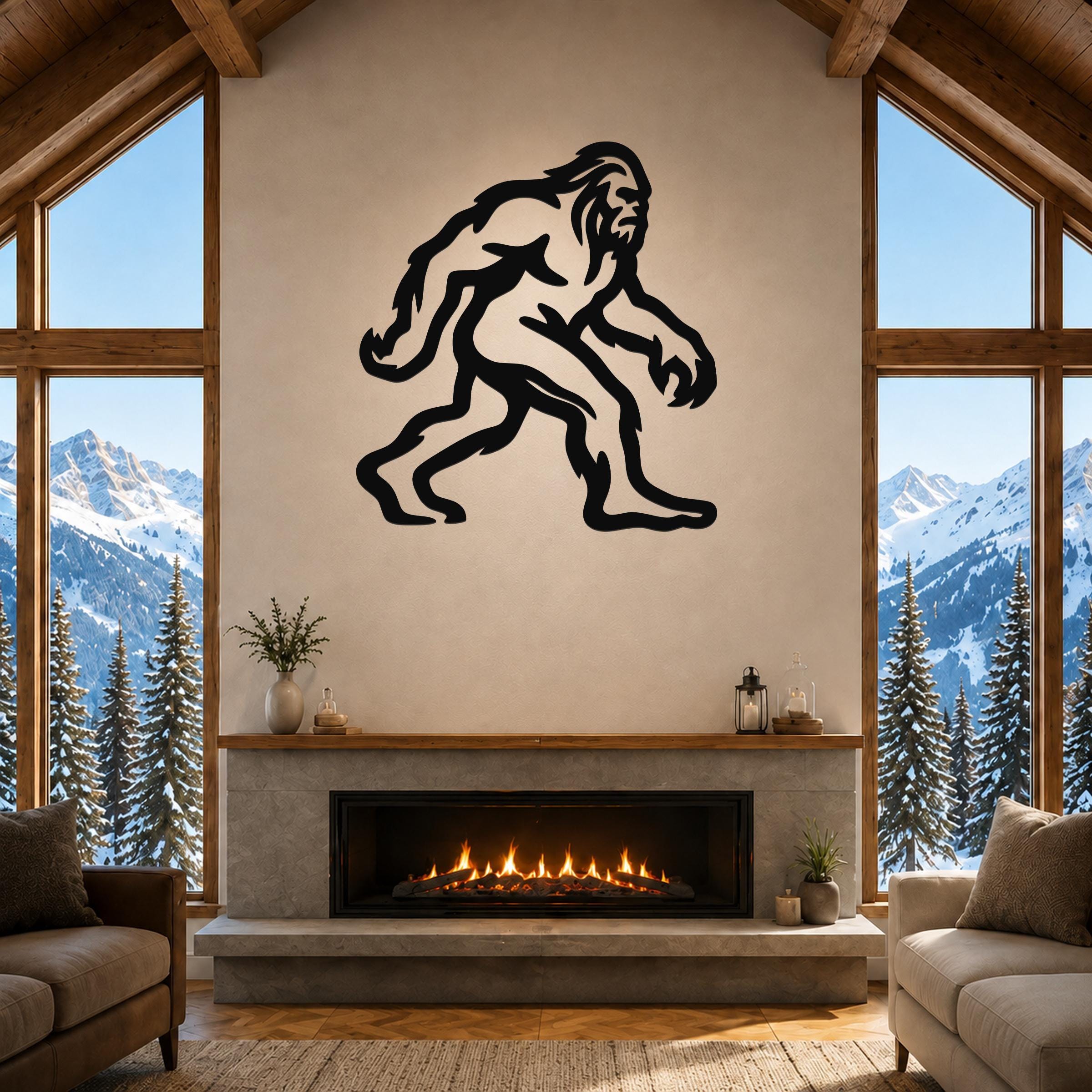 Black metal Bigfoot wall art silhouette with motion-line cutouts, mounted above a fireplace in a rustic living room with mountain views.