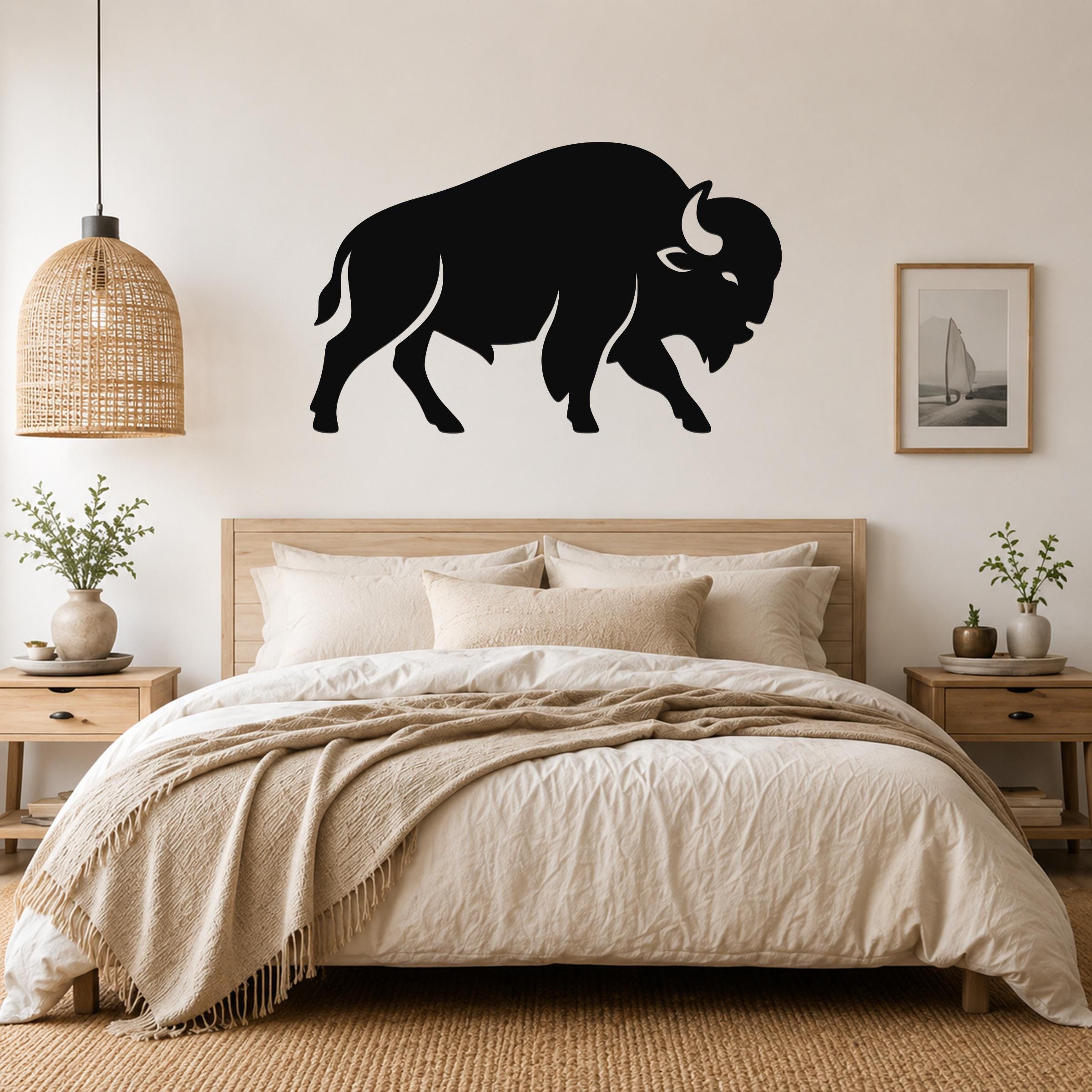 Black metal buffalo silhouette wall art mounted above a wooden bed in a neutral bedroom.