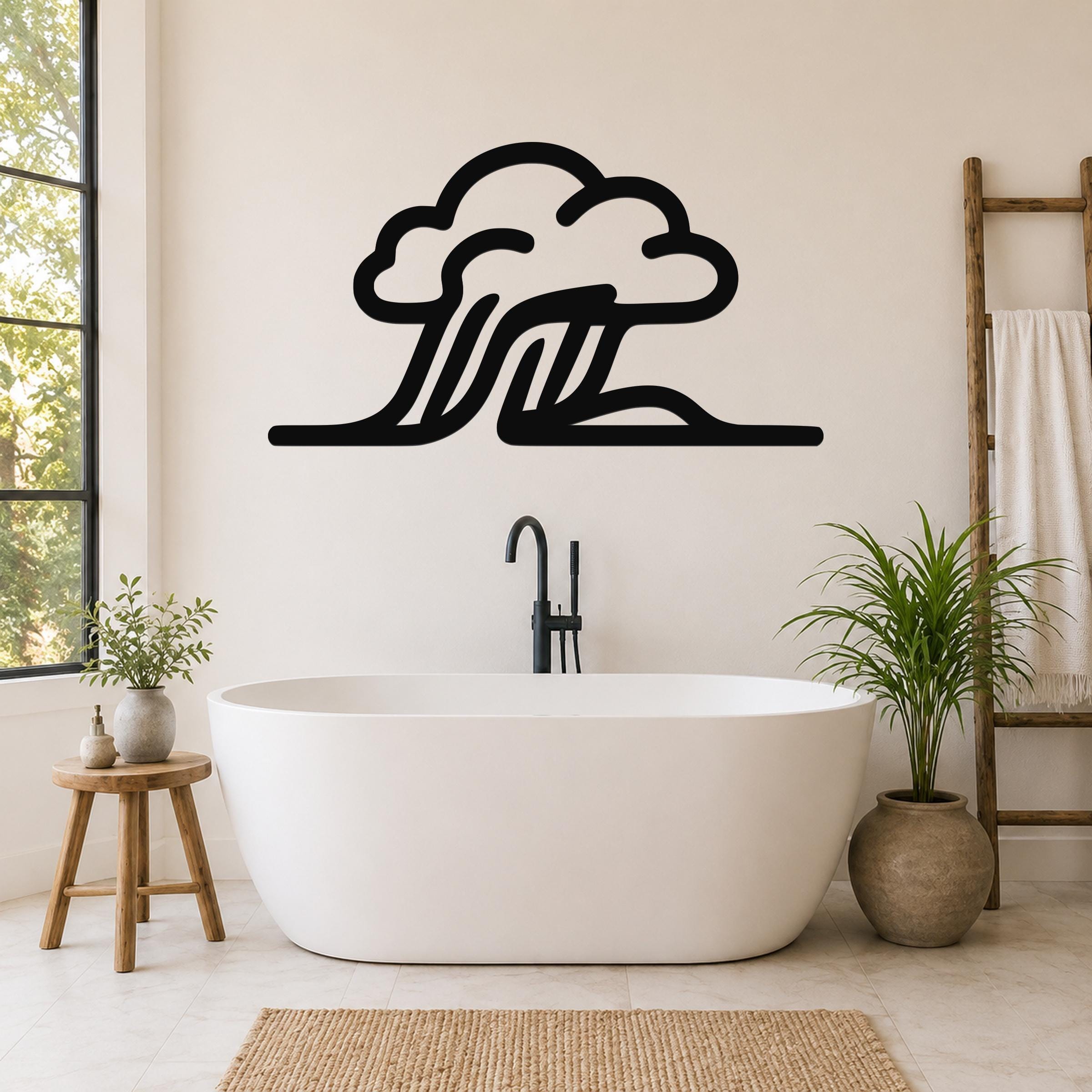 Black metal wall art in a cloud and wave silhouette design, mounted on a bathroom wall above a freestanding tub.