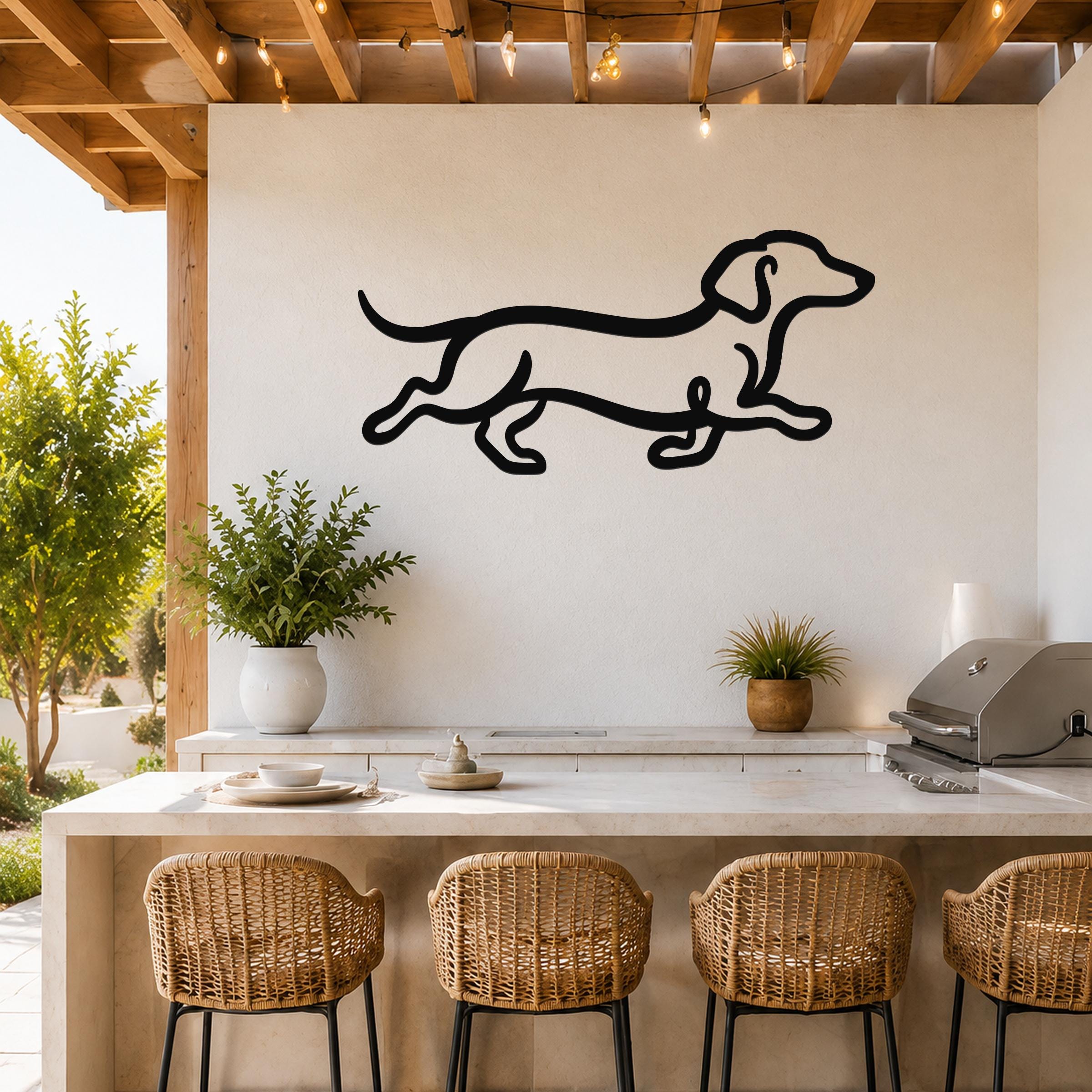 Black metal dachshund wall art with a running silhouette, mounted on a white outdoor wall above a kitchen counter.