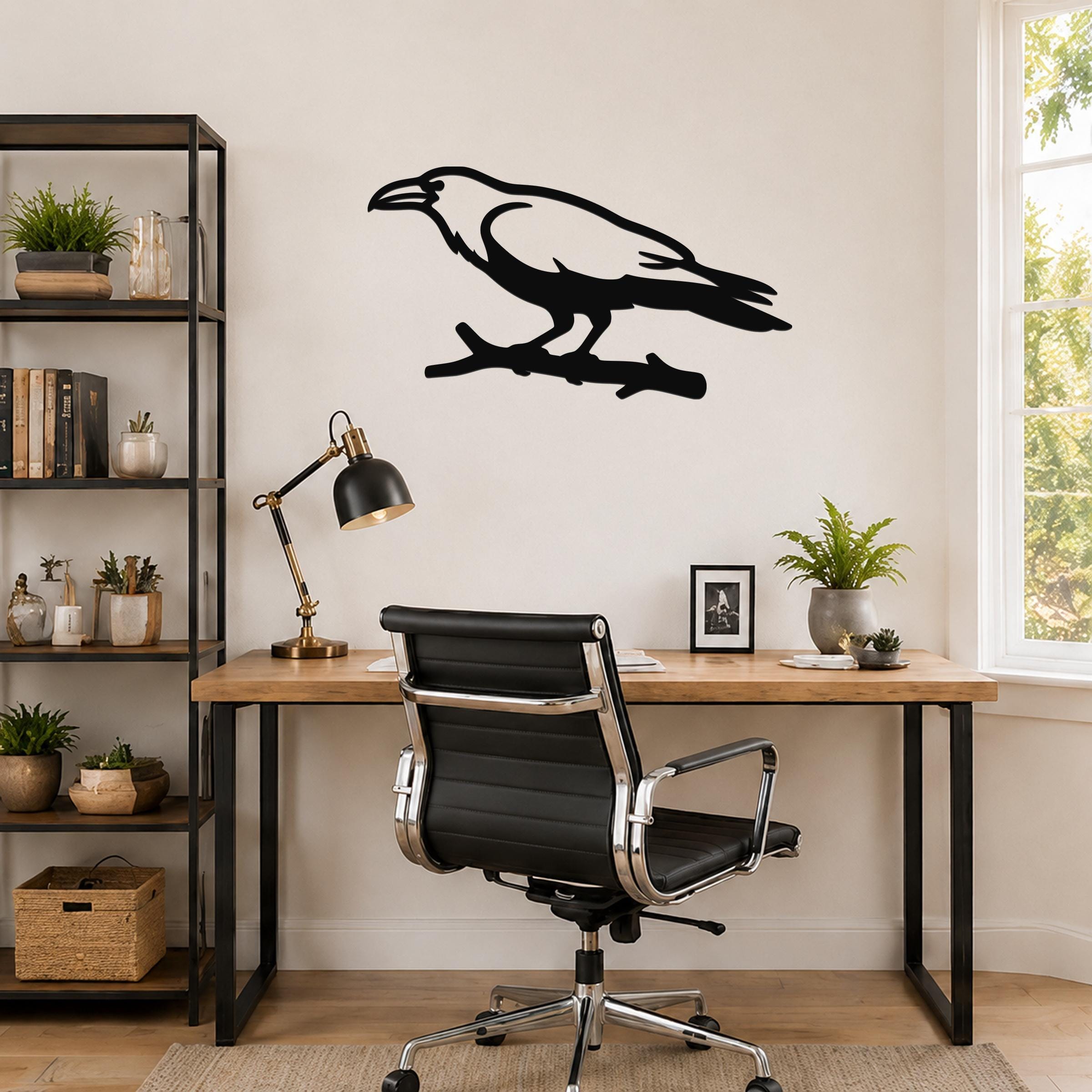 Black metal raven wall art silhouette perched on a branch, mounted above a wooden desk in a home office.