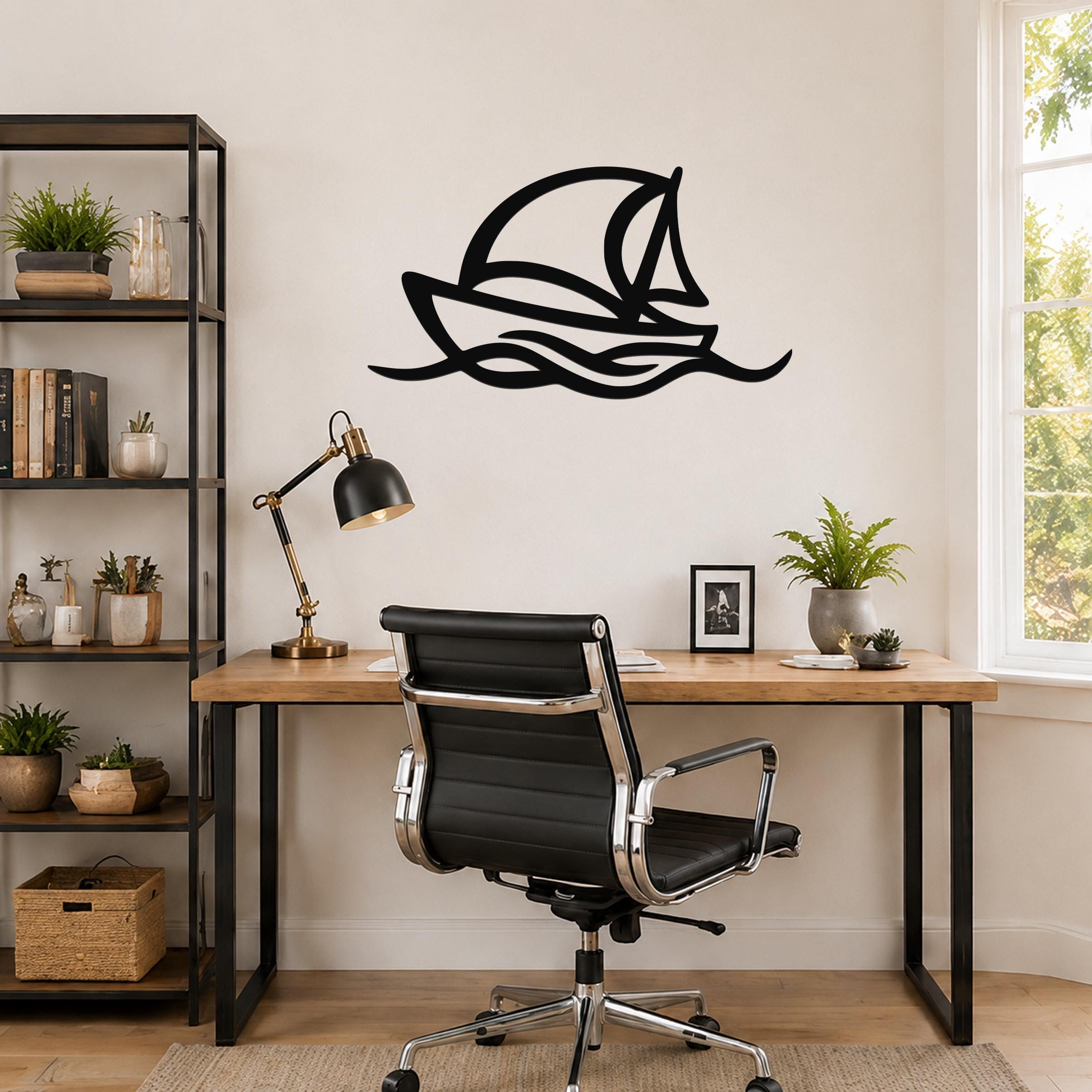 Black metal sailboat wall art with wave cutouts, mounted above a wooden desk in a home office.