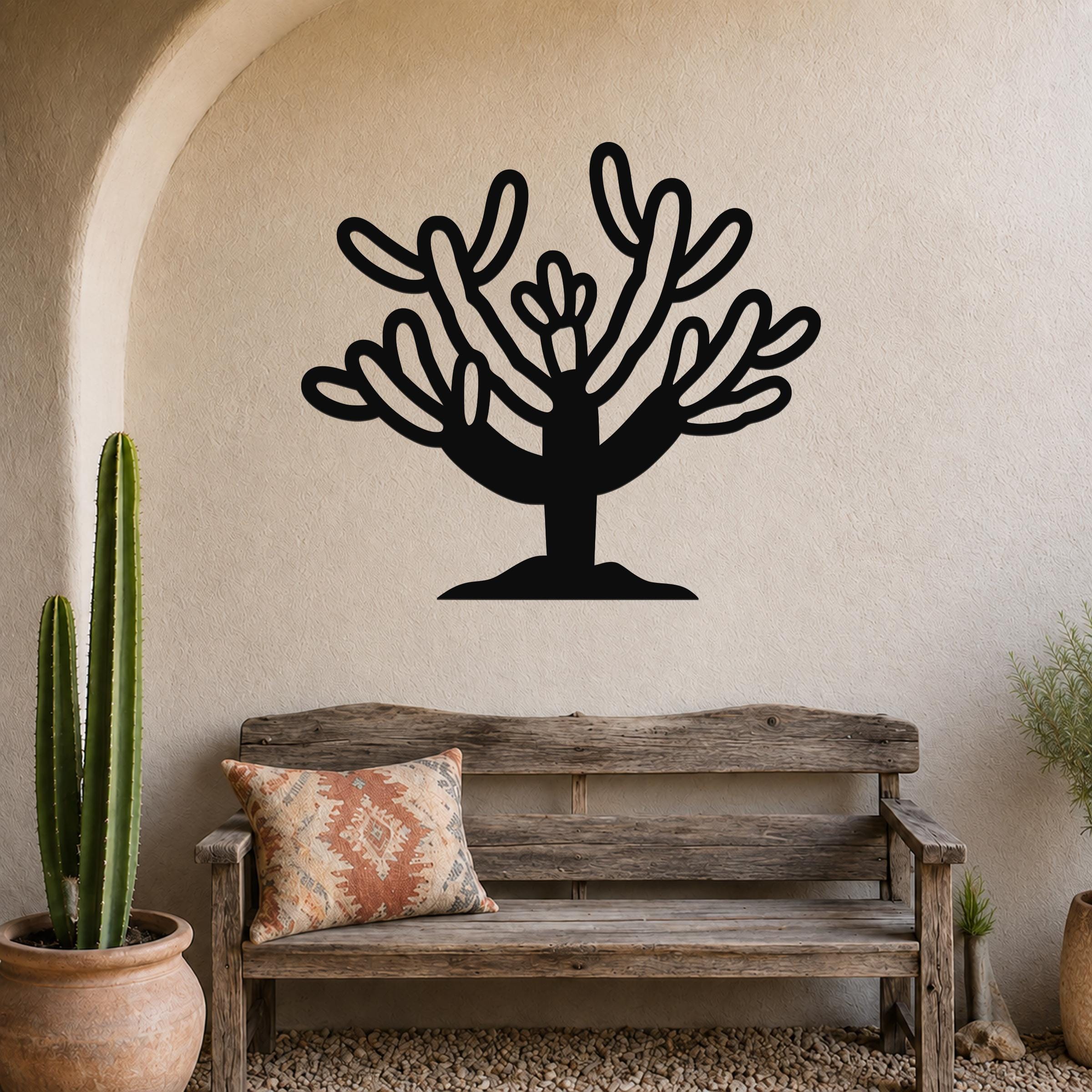 Black metal Cholla cactus wall art with branching cutouts, mounted on a textured beige wall above a wooden bench in a southwestern-style entryway.