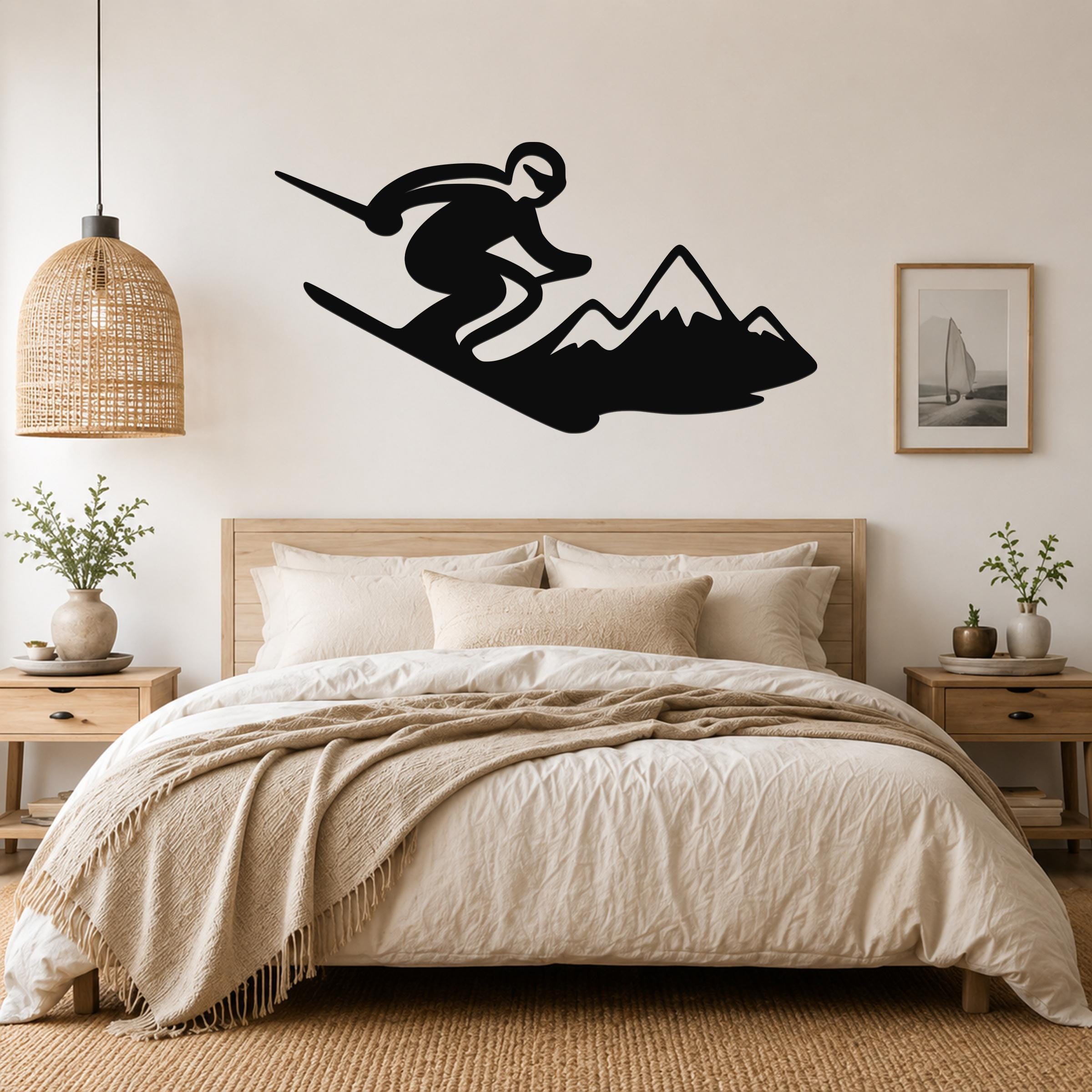Black metal wall art silhouette of a skier in motion above a bed, mounted on a light-colored bedroom wall.