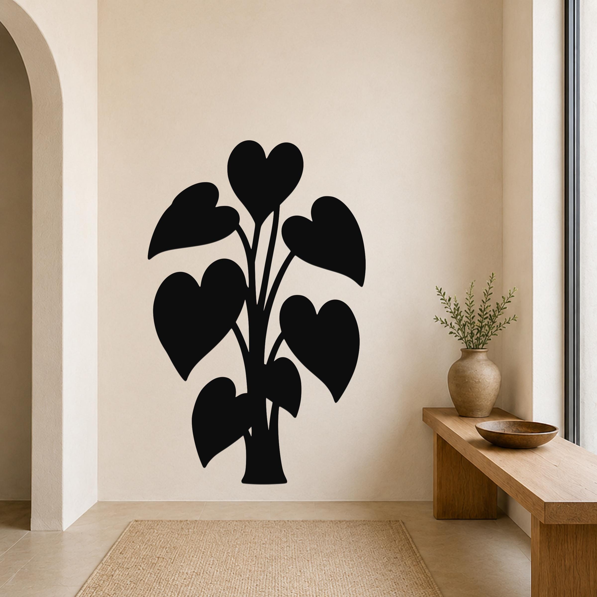 Black metal wall art in the silhouette of a heart-leaf philodendron plant, mounted on a beige living room wall above a woven rug.