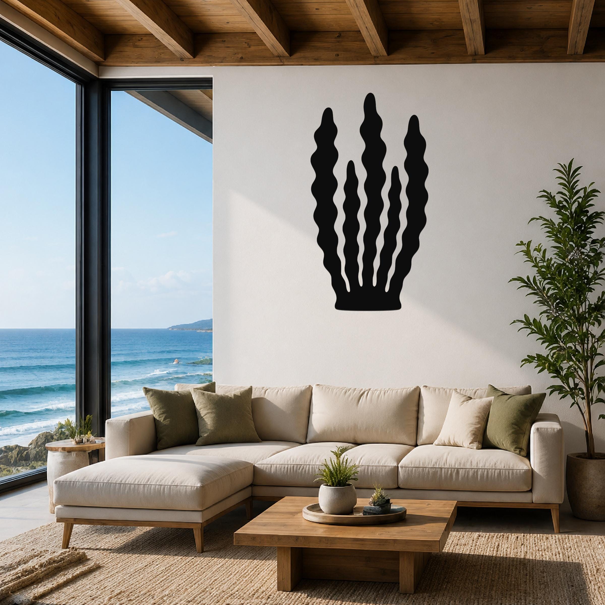Black metal kelp wall art with wavy vertical cutouts, mounted on a white living room wall above a beige sectional sofa.