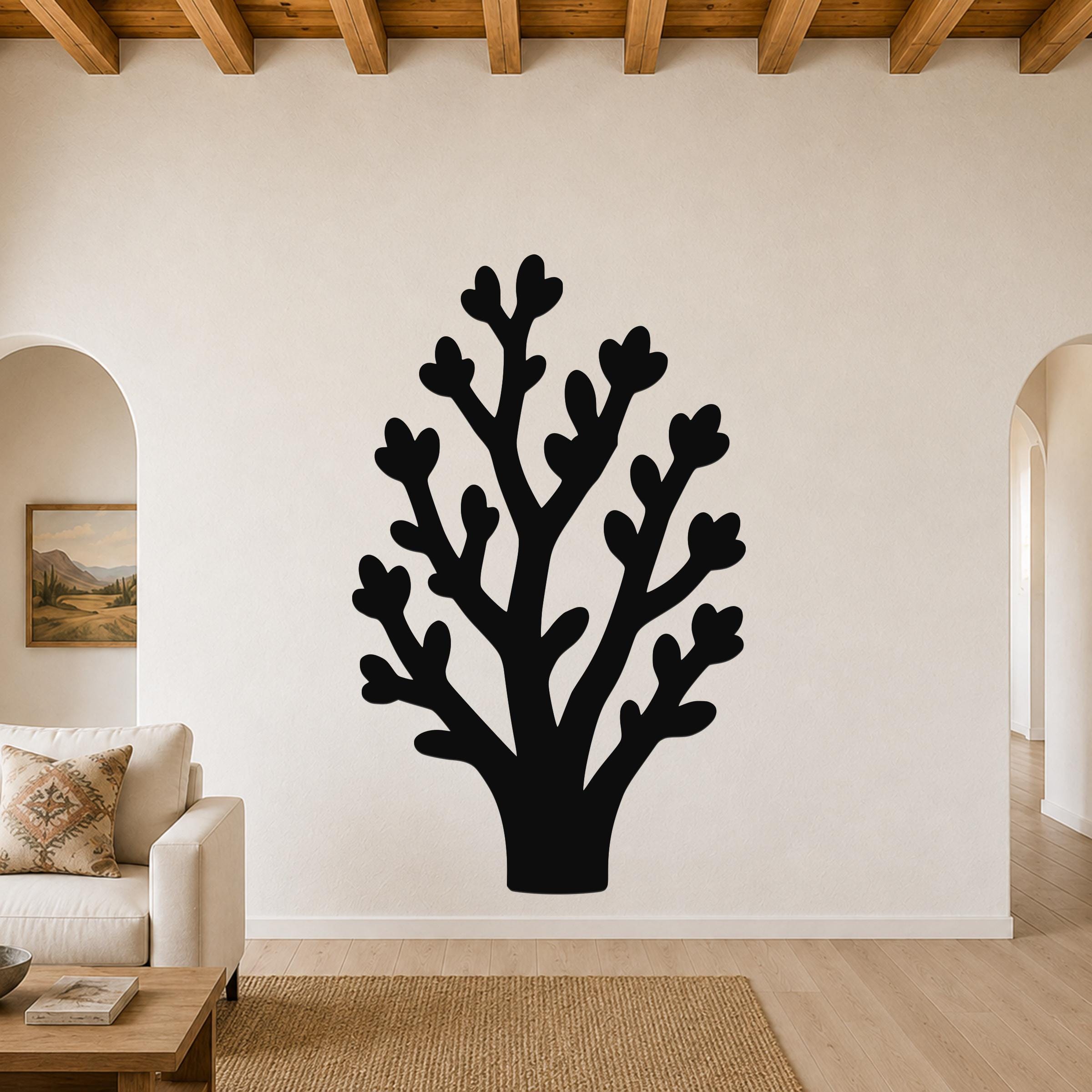 Black metal wall art in a tree silhouette with heart-shaped leaf cutouts, mounted on a living room wall above a sofa.