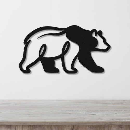 Black metal bear wall art with a cutout silhouette design, mounted on a white wall above a wooden surface.