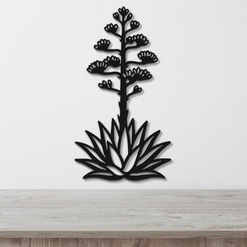 Black metal agave wall sculpture with blooming flower cutouts, mounted on a white wall above a light wood counter.