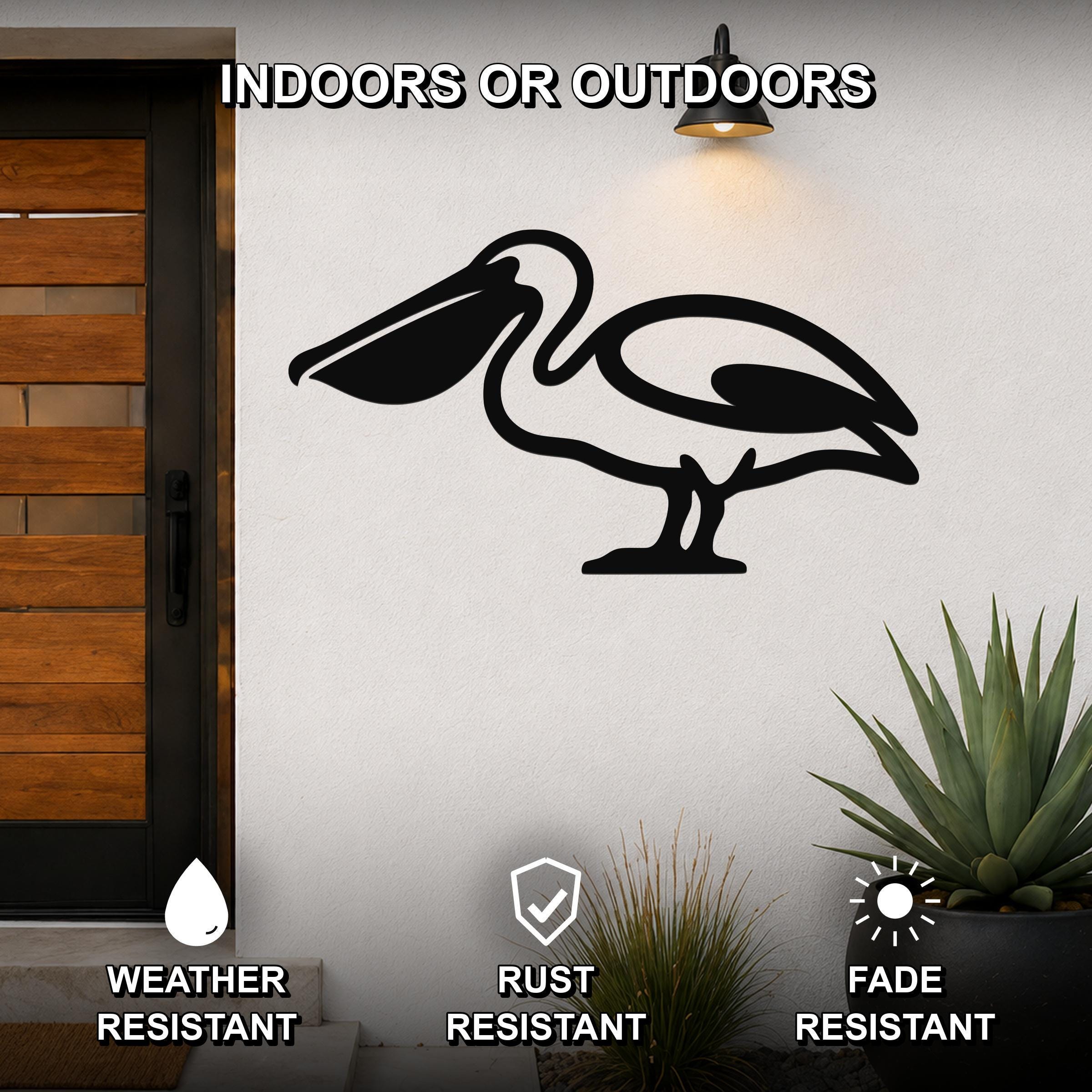 Black metal pelican wall art silhouette mounted on an outdoor wall beside a wooden door, with a potted succulent nearby.