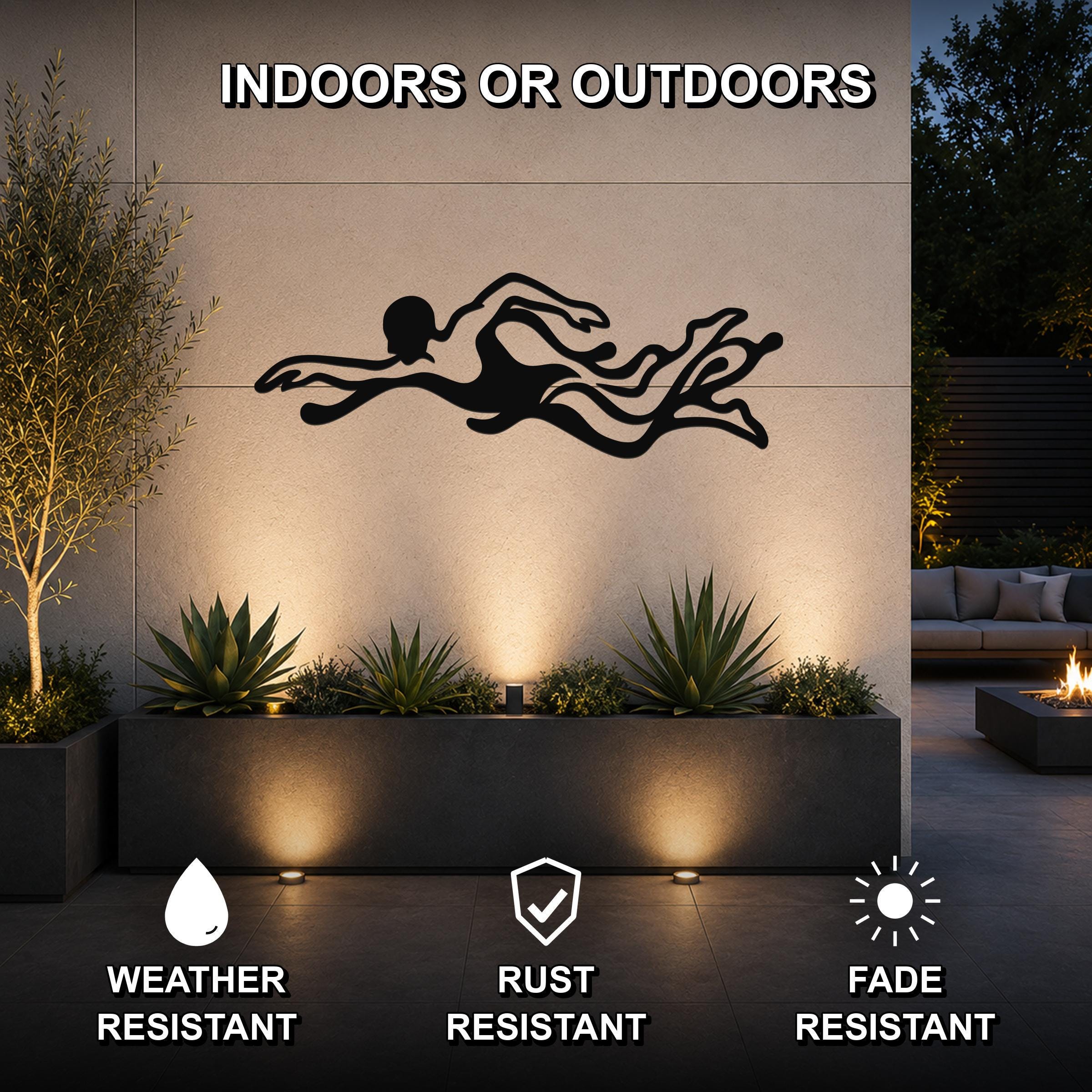 Black metal swimmer wall art with flowing motion cutouts, mounted on an outdoor wall above a planter in a patio setting.