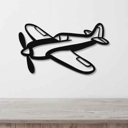 Black metal airplane wall art with a bold silhouette design, featuring cutout details of the propeller and cockpit, mounted on a white wall above a wooden surface.
