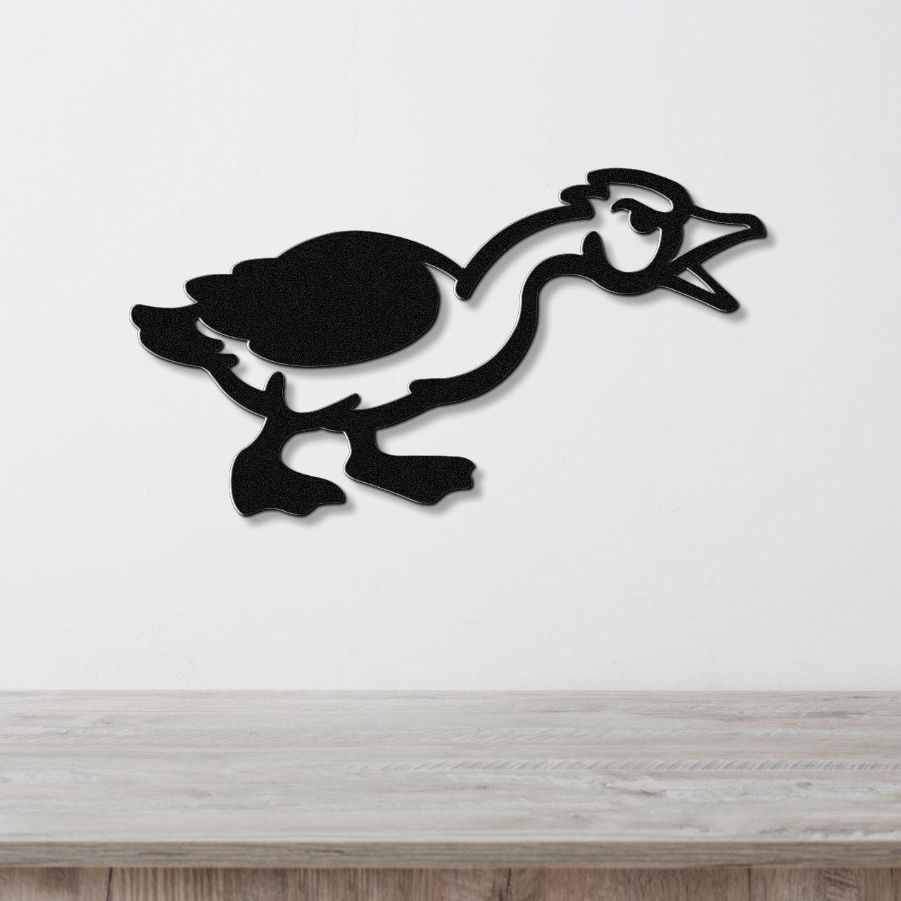 Black metal wall art silhouette of a goose in motion, mounted on a white wall above a light wood surface.