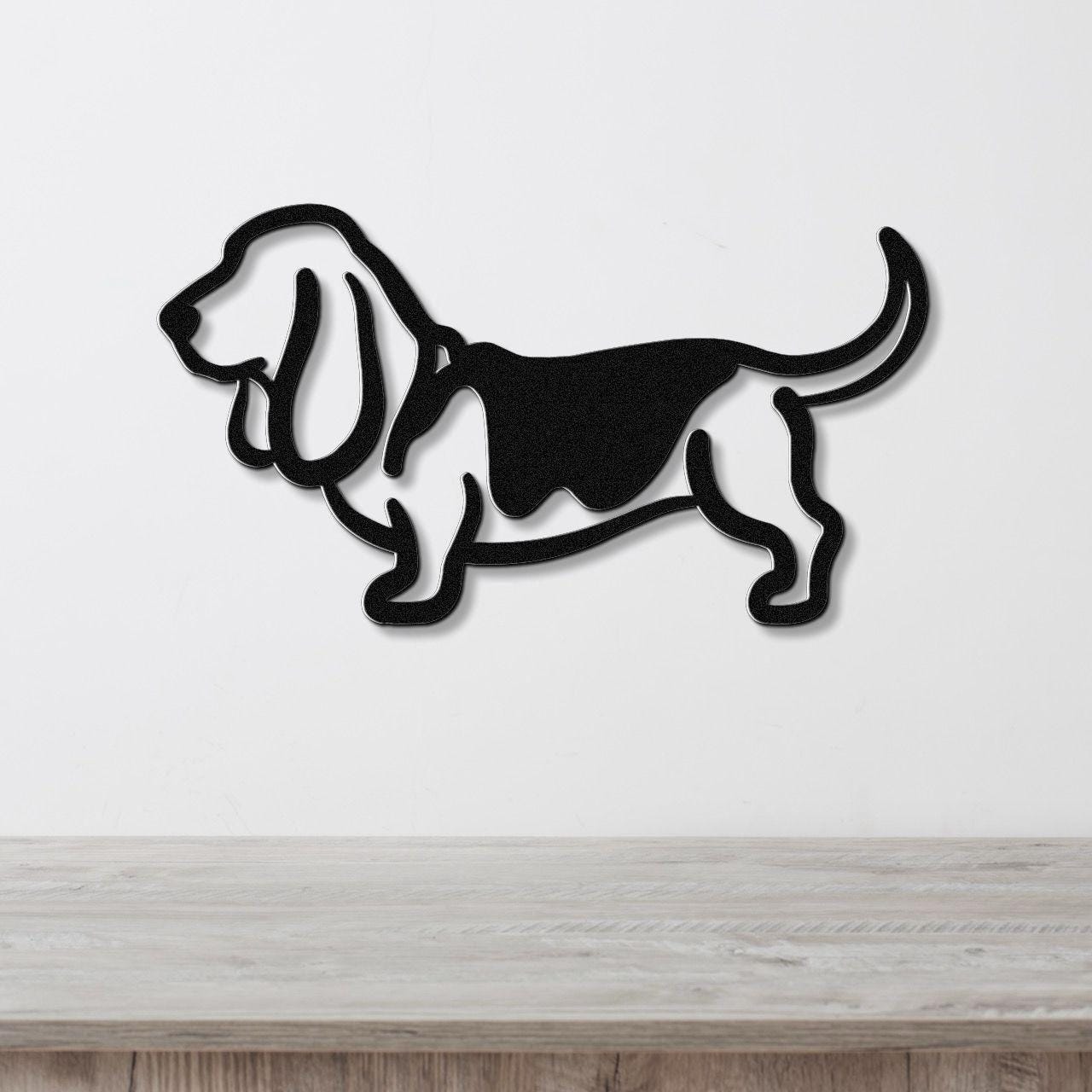 Black metal Basset Hound silhouette wall art with cutout details, mounted on a white wall above a light wood surface.