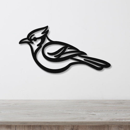 Black metal blue jay wall art with internal feather cutouts, mounted on a white wall above a light wood counter.