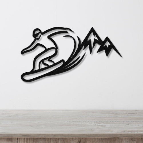 Black metal wall art silhouette of a snowboarder in motion with mountain peaks, mounted on a white wall above a light wood counter.