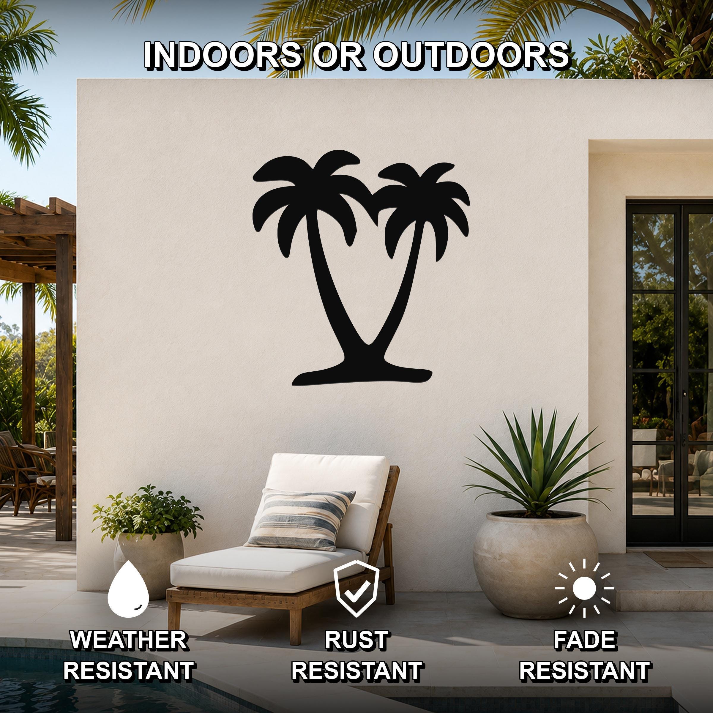 Black metal palm tree wall art with two silhouetted trees, mounted on an outdoor patio wall above a lounge chair.