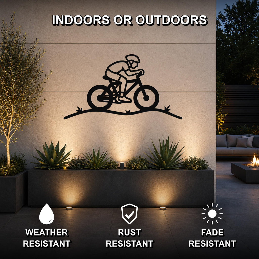 Black metal wall art featuring a cyclist silhouette on a hill, mounted on an outdoor wall above a planter in a patio setting.