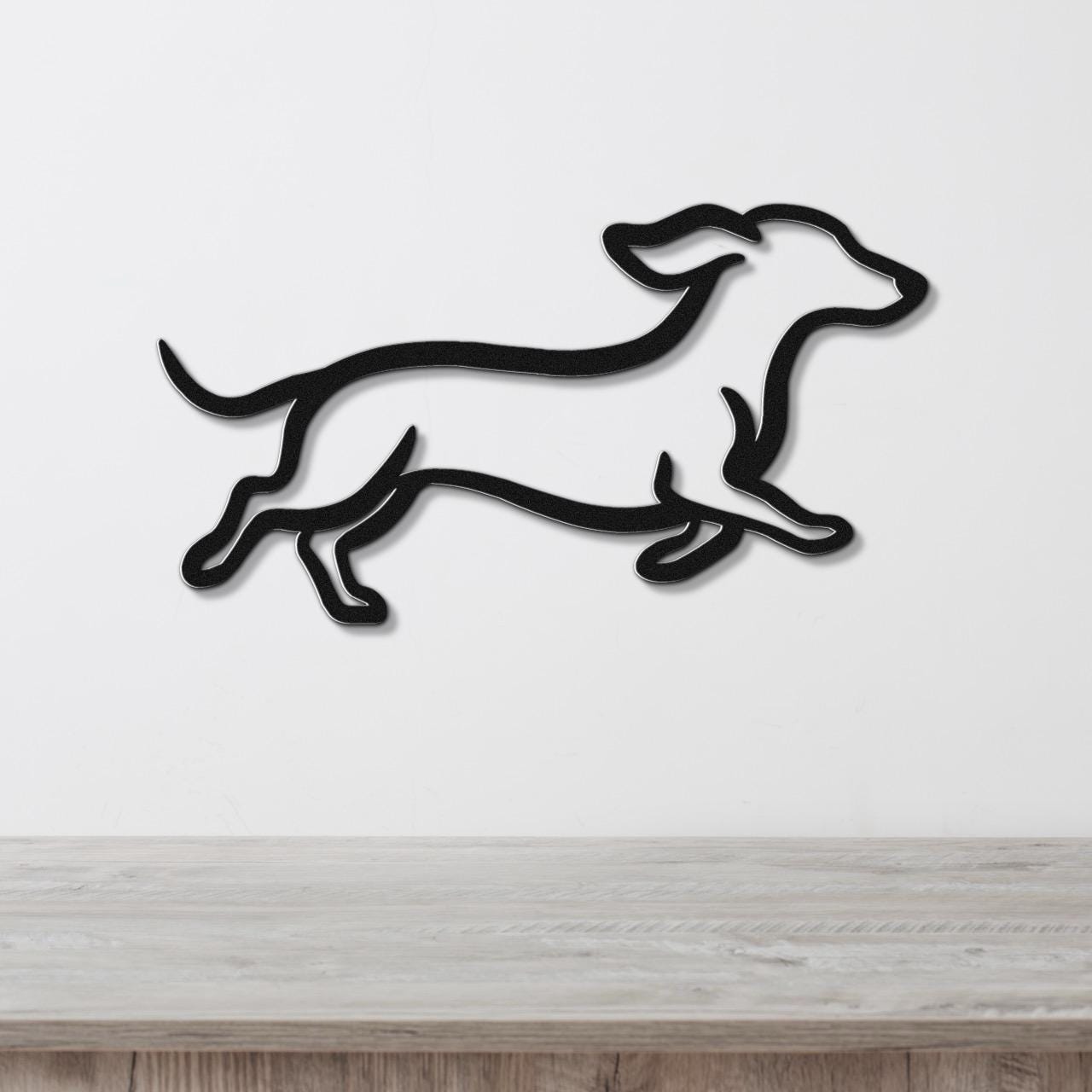 Black metal dachshund wall art in a running silhouette, mounted on a white wall above a light wood surface.