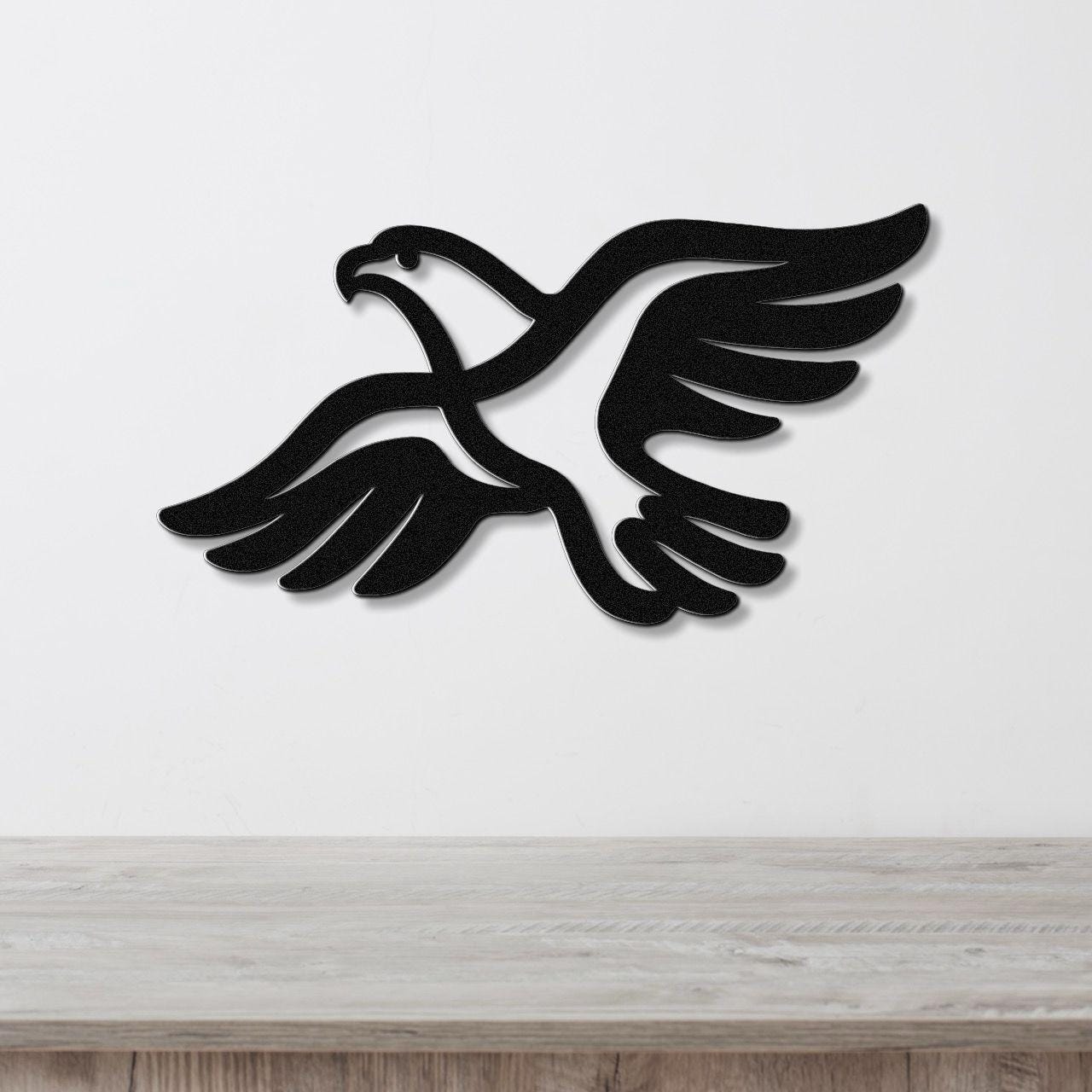 Black metal eagle wall art with outstretched wings and internal cutout details, mounted on a white wall above a light wood countertop.