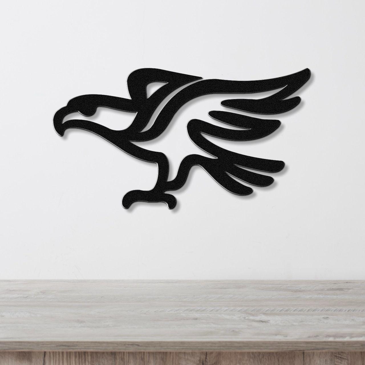 Black metal eagle wall art with a bold silhouette and cutout wing details, mounted on a white wall above a light wood counter.
