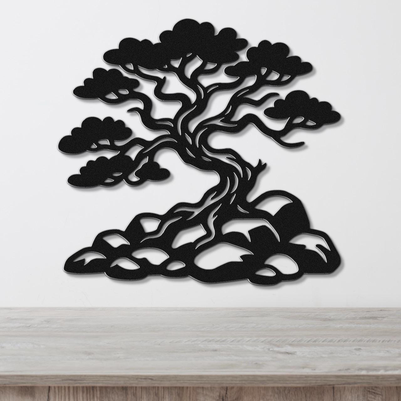 Black metal wall art silhouette of a juniper tree with intricate branches and roots, mounted on a white wall above a wooden counter.