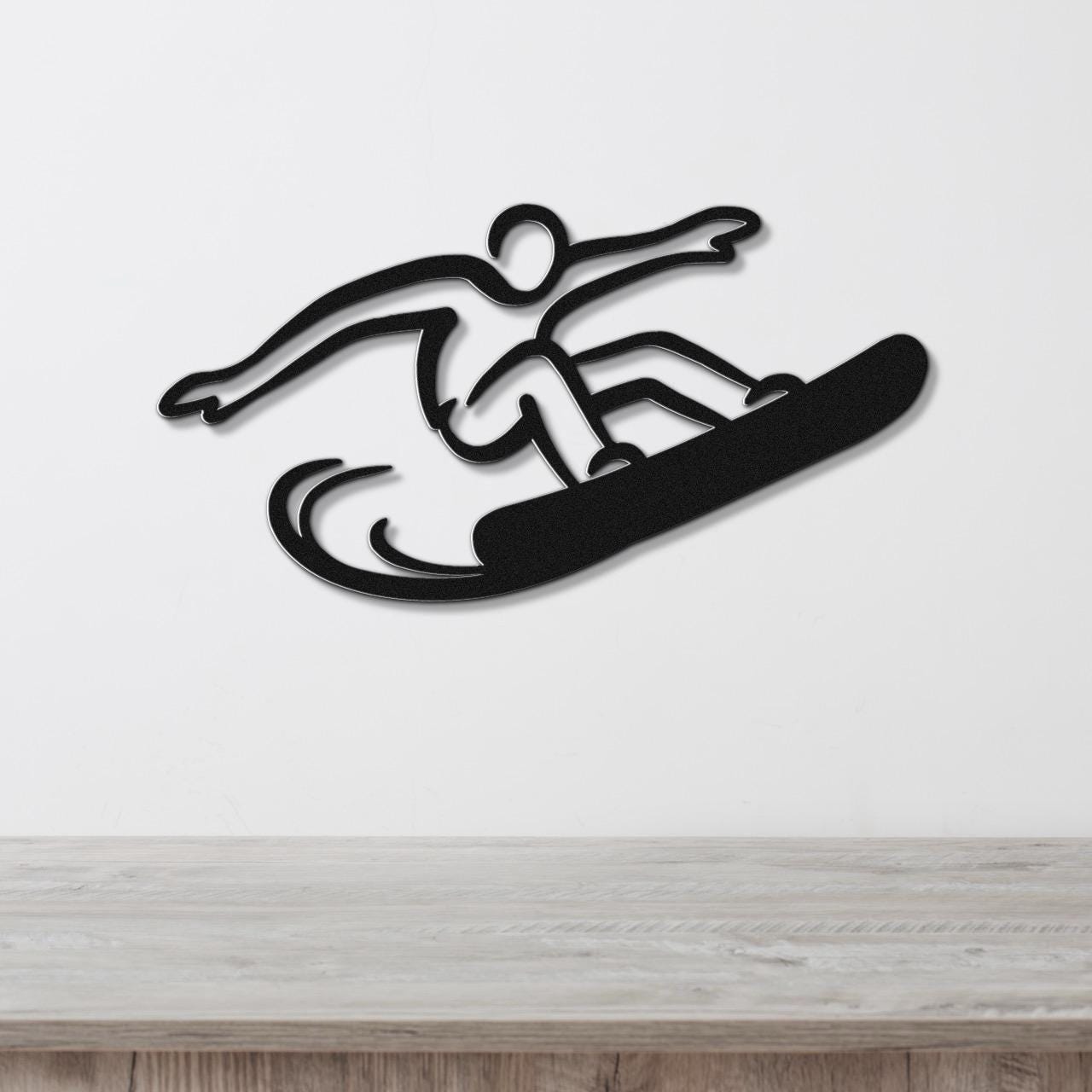 Black metal snowboarder wall art with a dynamic silhouette and motion lines, mounted on a white wall above a wooden counter.