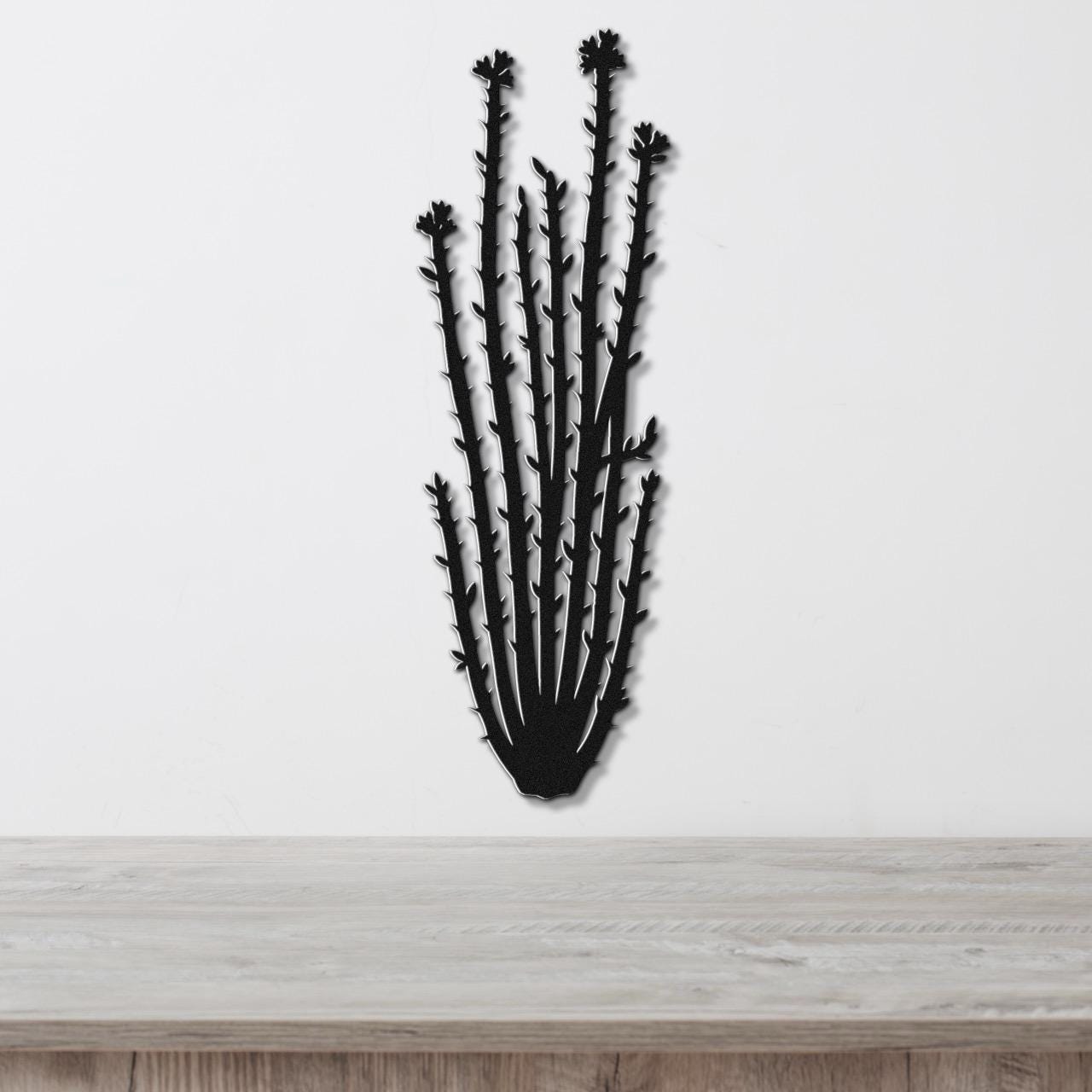 Black metal ocotillo wall art with spiny branches and flower cutouts, mounted on a white wall above a light wood counter.