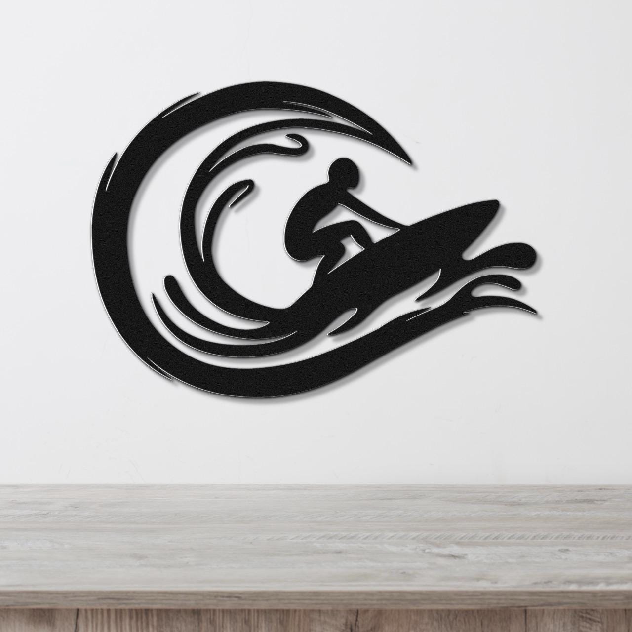 Black metal wall art featuring a surfer silhouette riding a wave, mounted on a white wall above a wooden surface.
