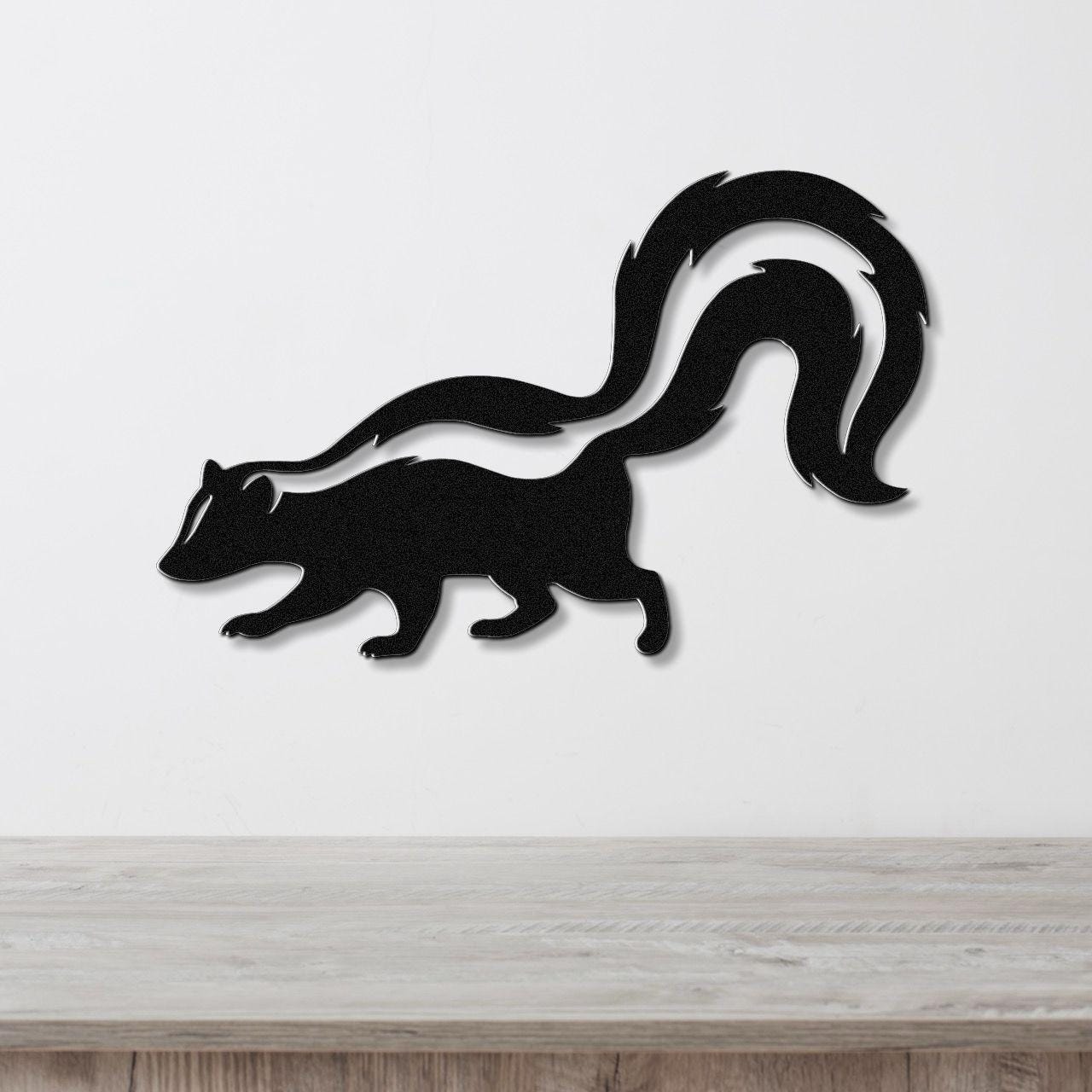 Black metal skunk wall art with a white stripe cutout, mounted on a white wall above a wooden surface.