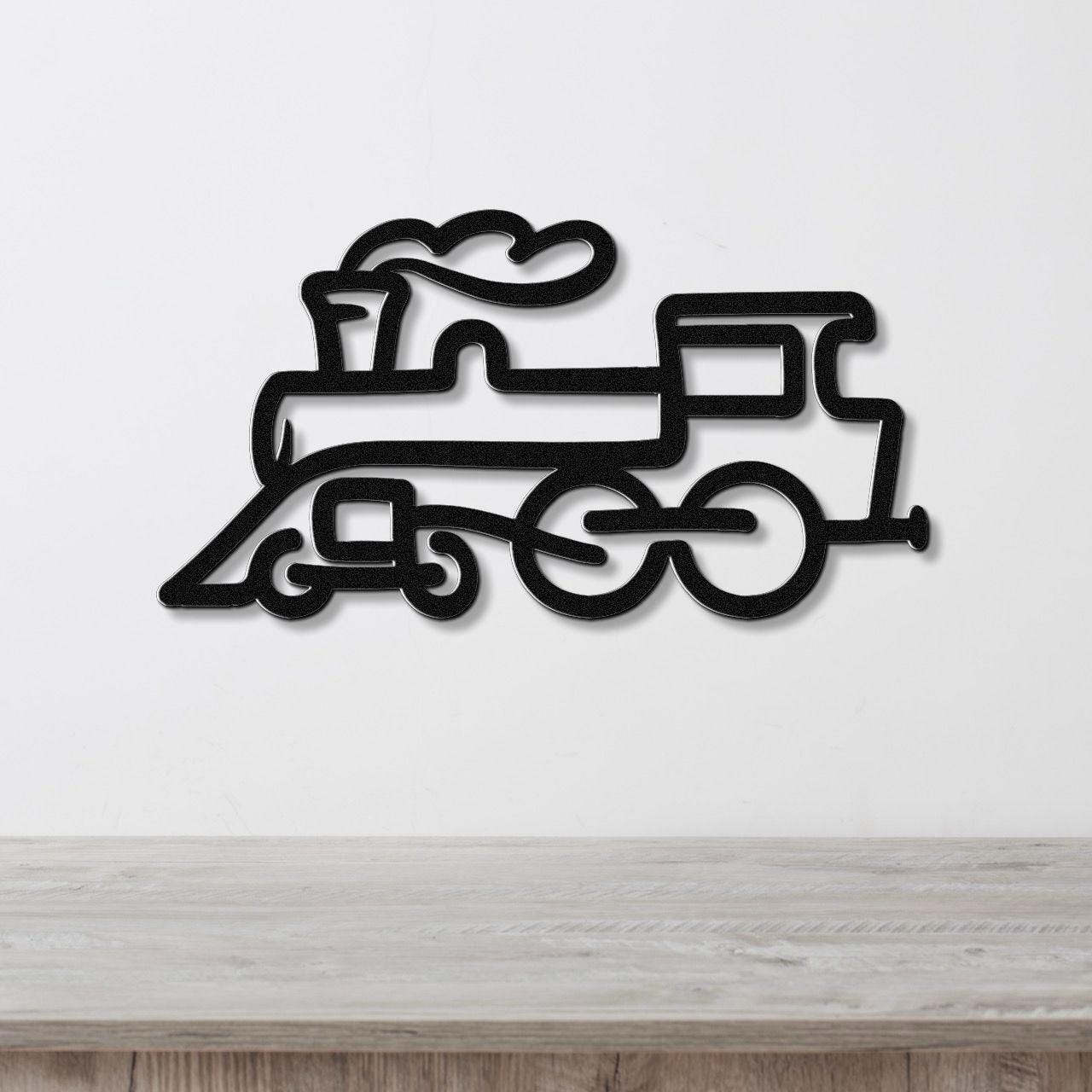 Black metal train wall art with a silhouette design of a steam locomotive, mounted on a white wall above a wooden surface.