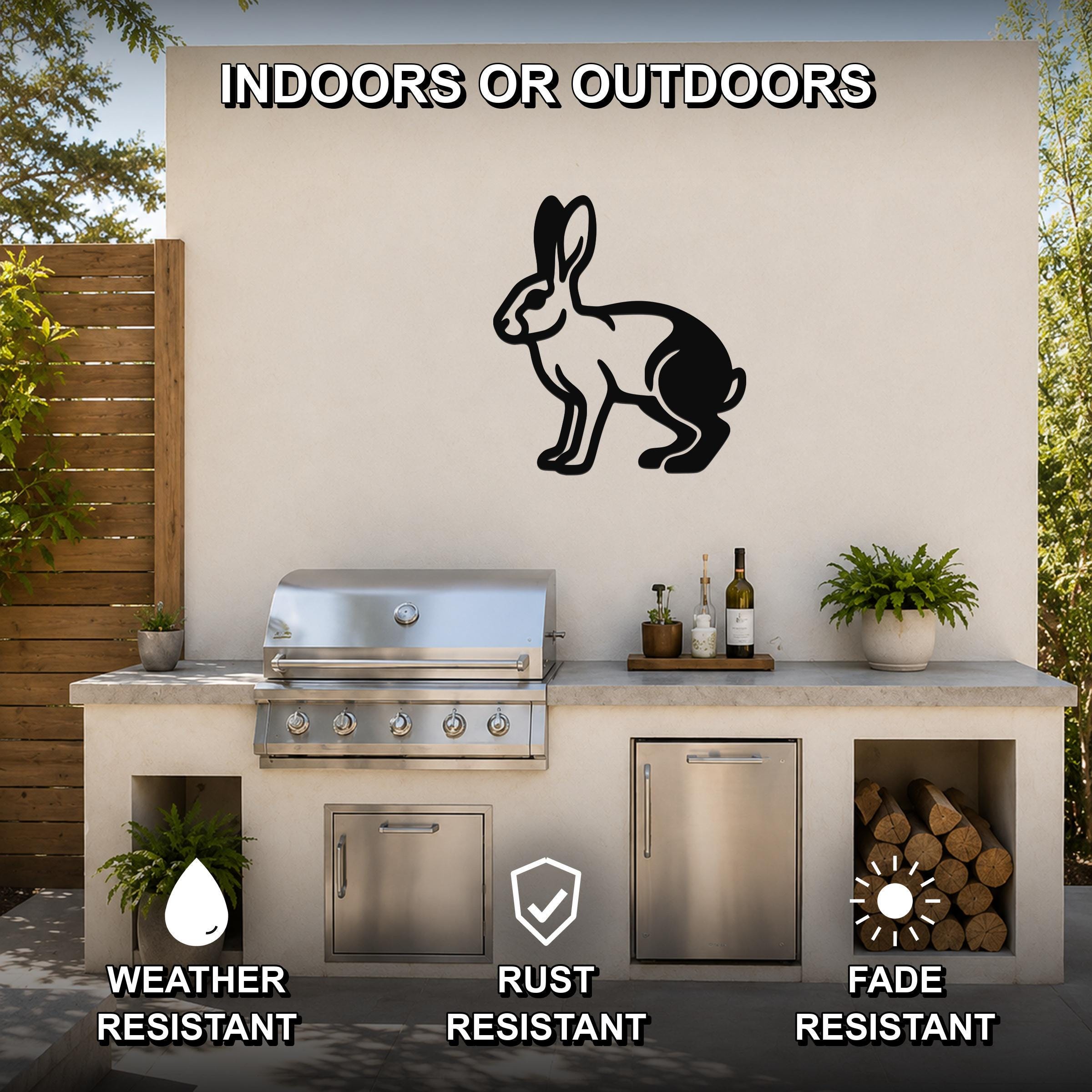 Black metal jackrabbit wall art silhouette mounted on an outdoor patio wall above a stainless steel grill and counter.