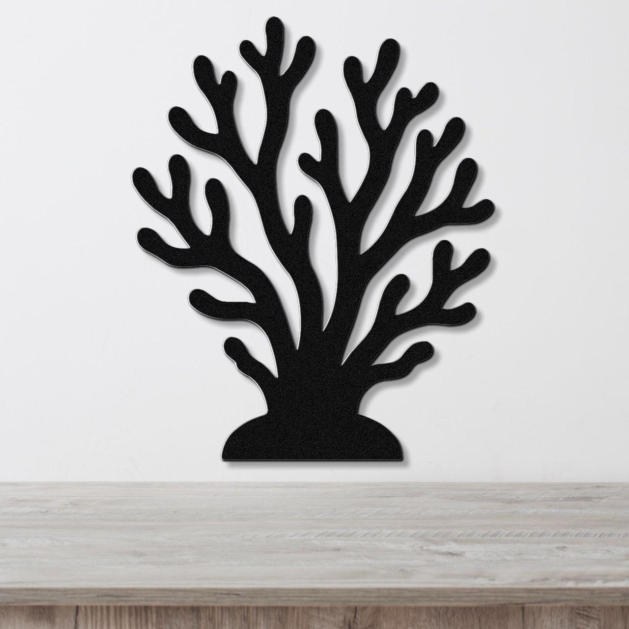 Black metal coral wall art with branching cutouts, mounted on a white wall above a light wood countertop.