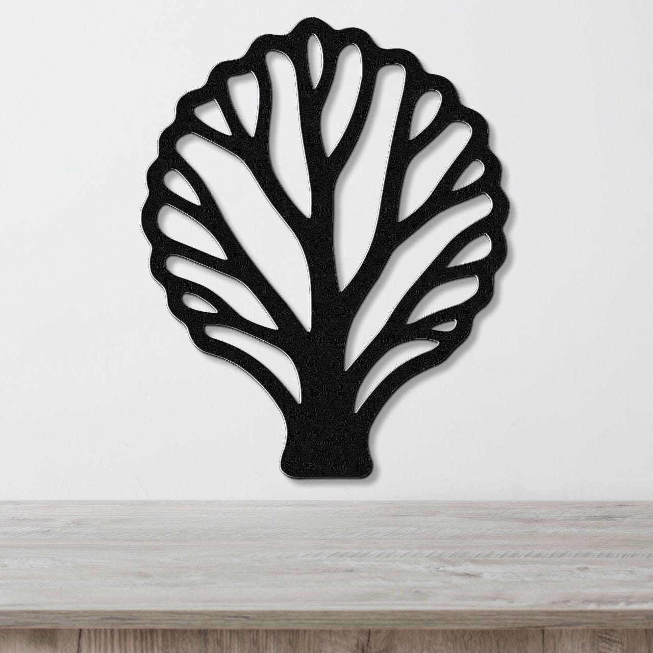 Black metal wall art in a fan coral silhouette with intricate cutout branches, mounted on a white wall above a light wood surface.