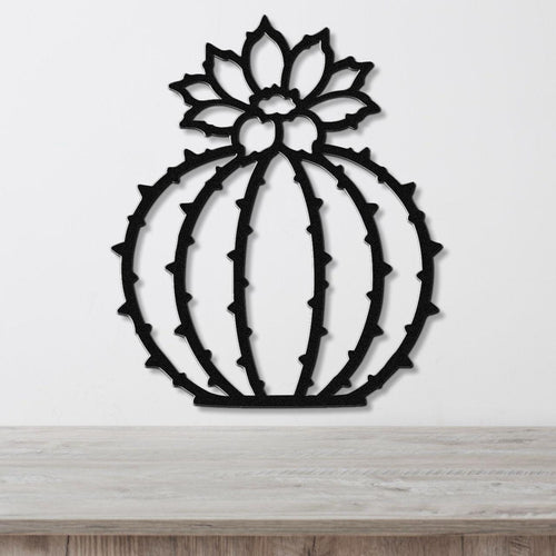 Black metal barrel cactus wall art with flower and spine cutouts, mounted on a white wall above a light wood counter.