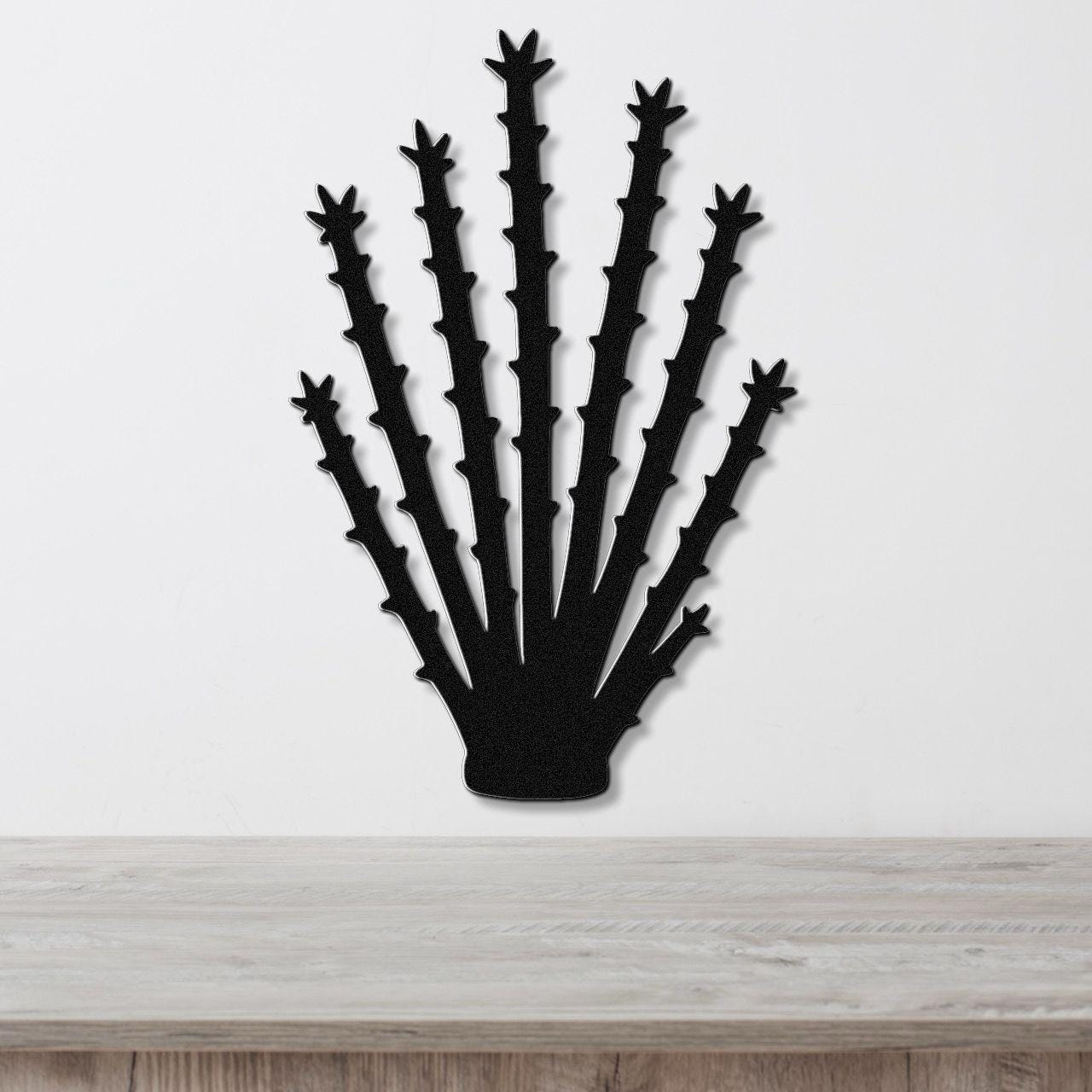 Black metal ocotillo wall art with spiky branch cutouts, mounted on a white wall above a light wood counter.